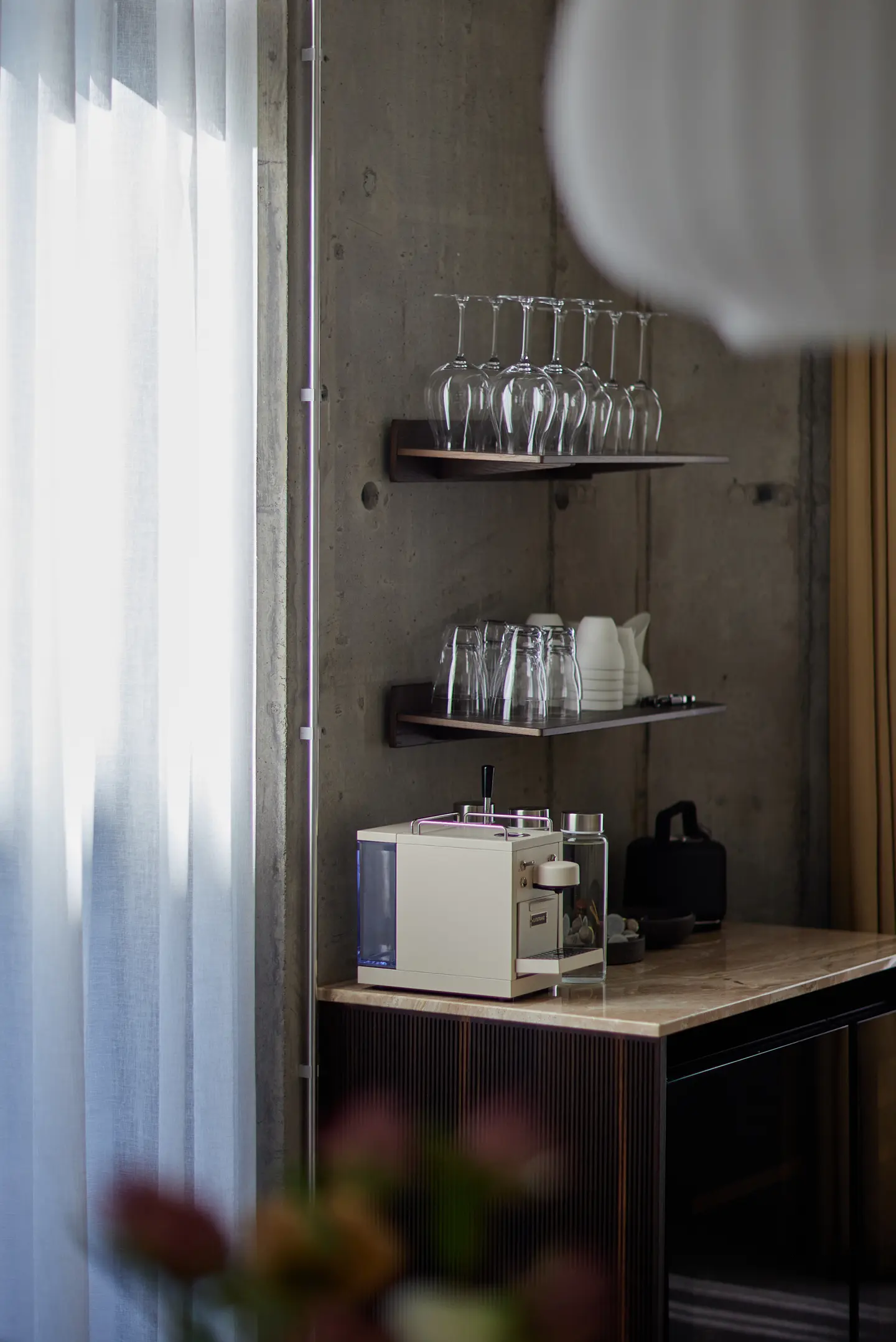 Meeting room drinks station with glassware, coffee machine, and concrete wall