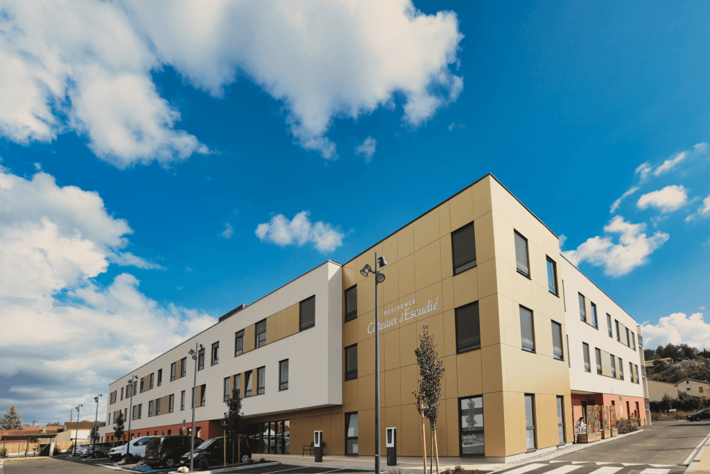 Classical cream and red colored residential building exterior with clear blue sky and white clouds