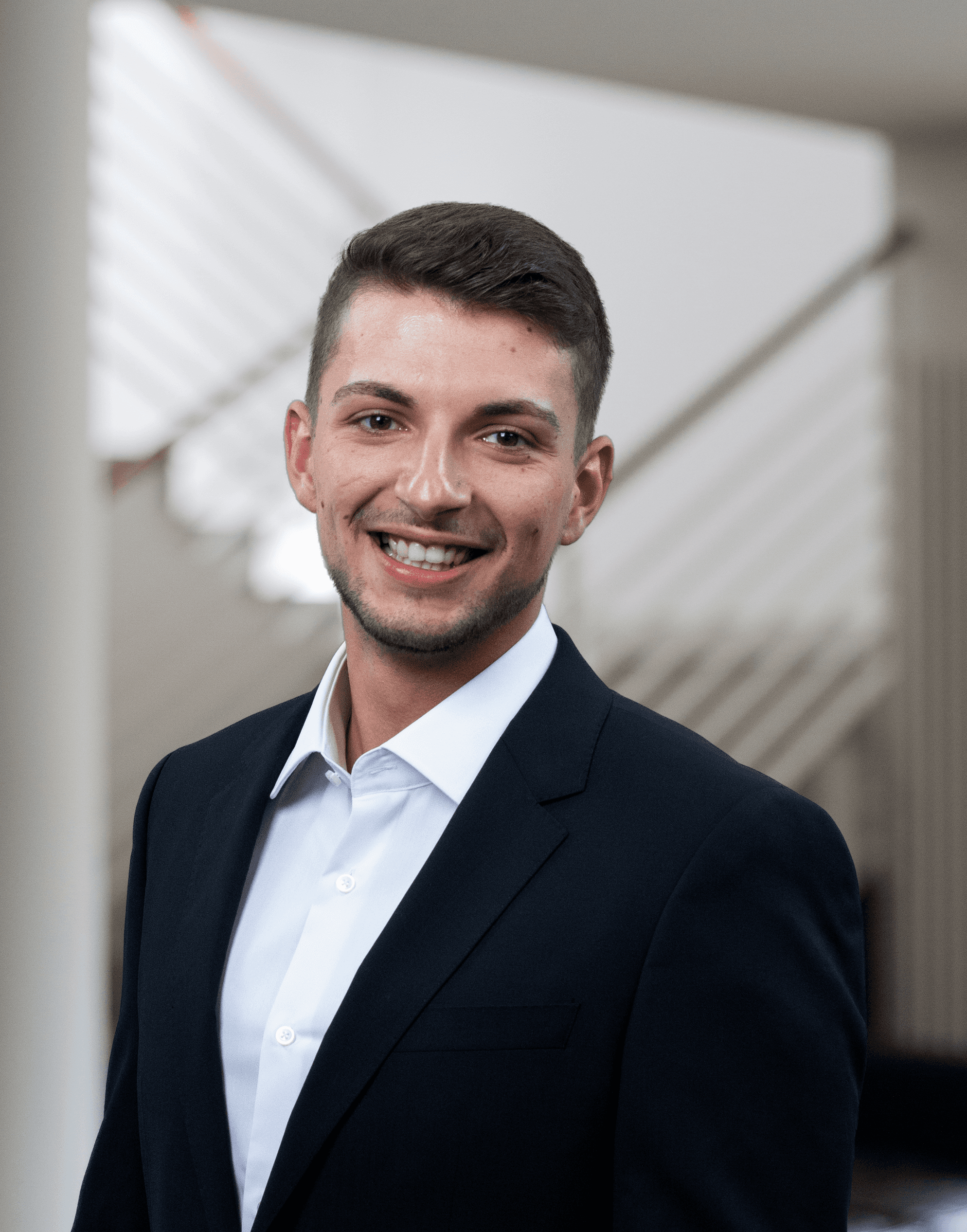 Ein junger Mann grinst im Hinterhof eines Firmengebäudes in die Kamera