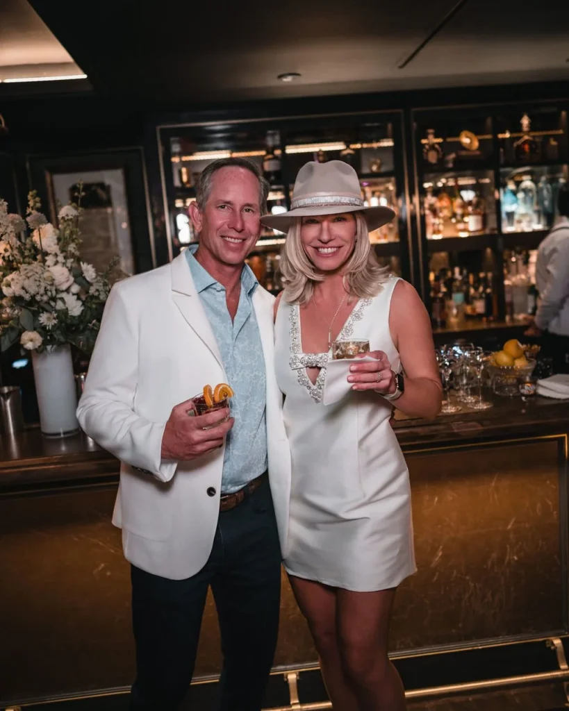 Two wedding guests posing together at a bar