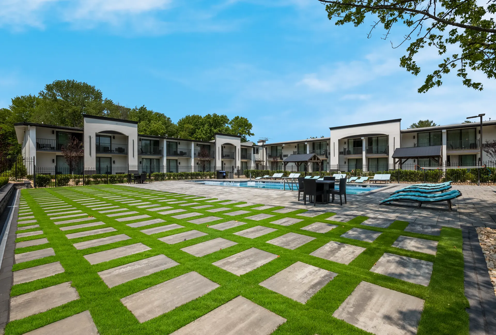An outdoor pool area with lounge chairs and a building in the background.