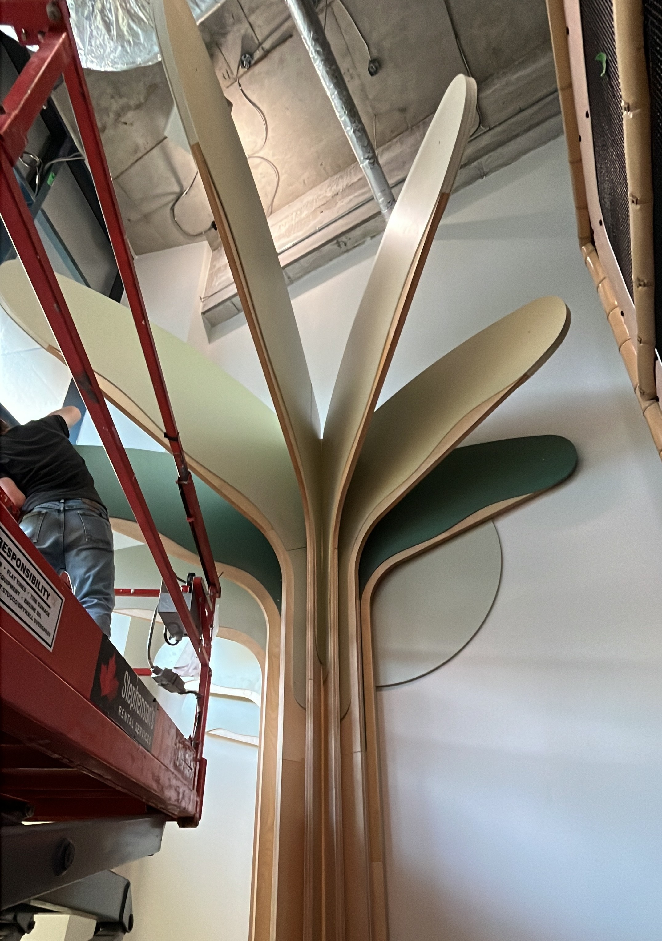 A Fern Kids plywood tree structure being assembled on site from a lift