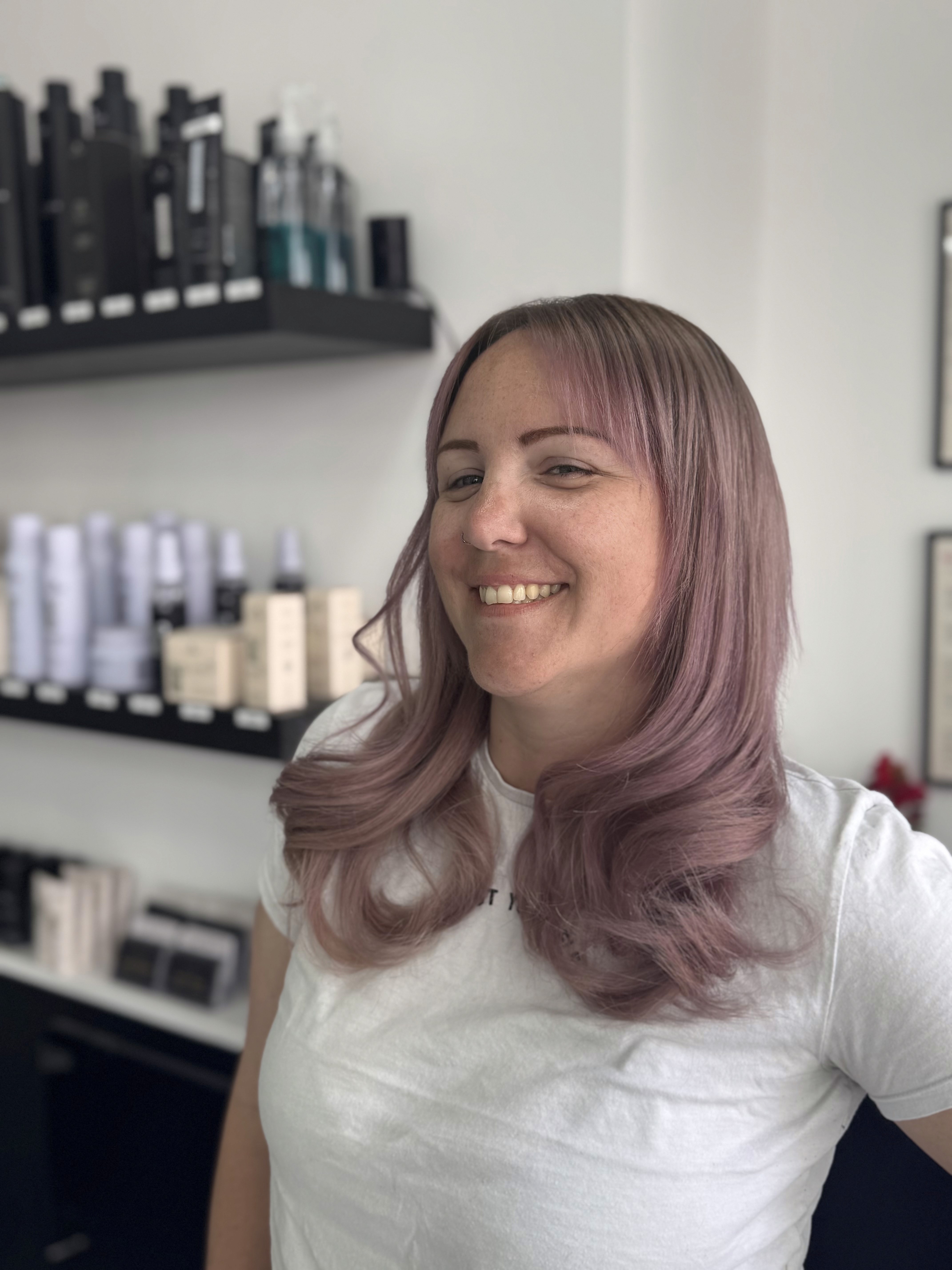 Smiling woman with long wavy brunette hair and blonde fringe