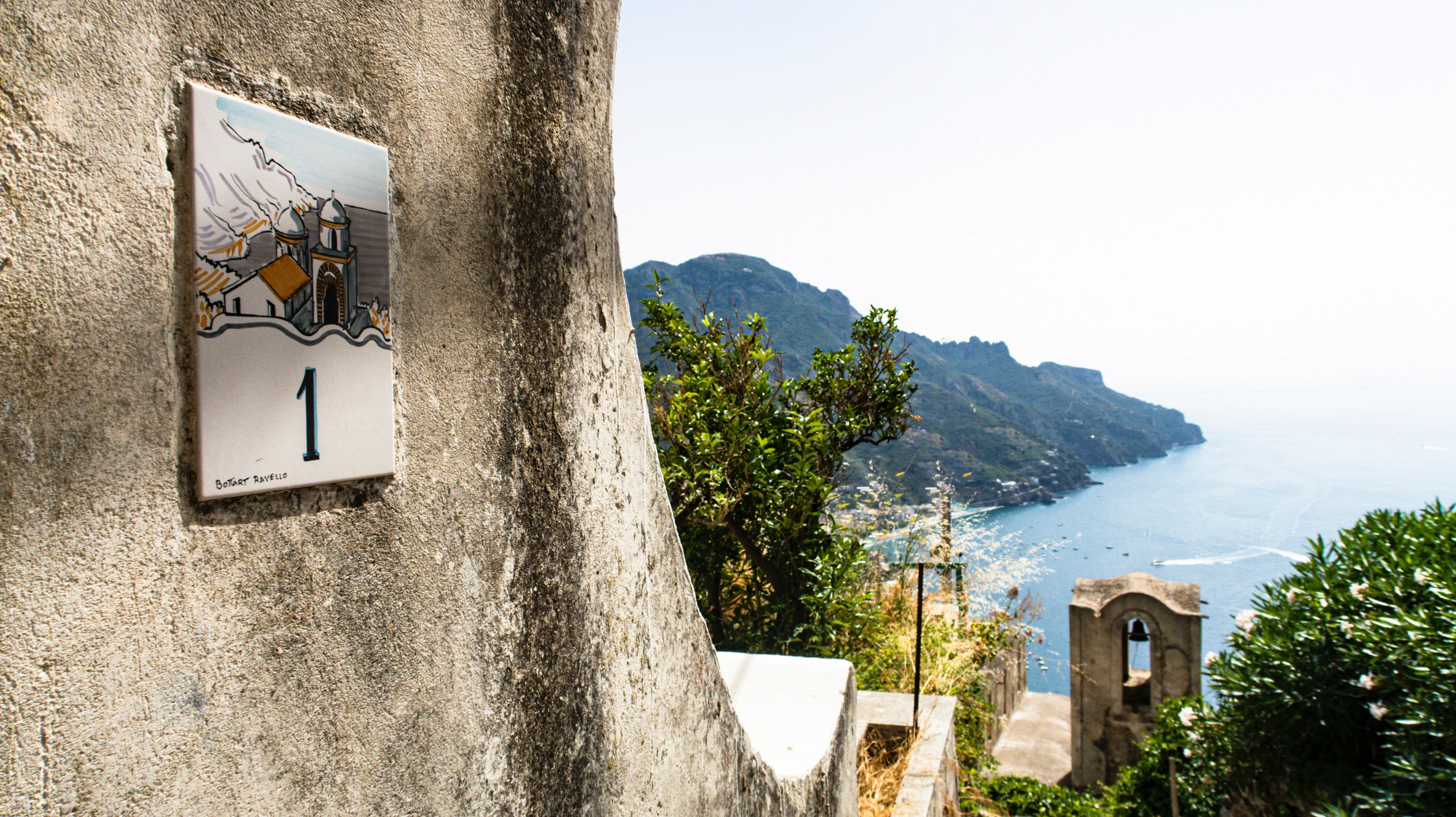 Top down perspective from a whitewashed vacation rental in Ravello revealing sweeping vistas of the Italian village, surrounding cliffs, and Mediterranean ocean