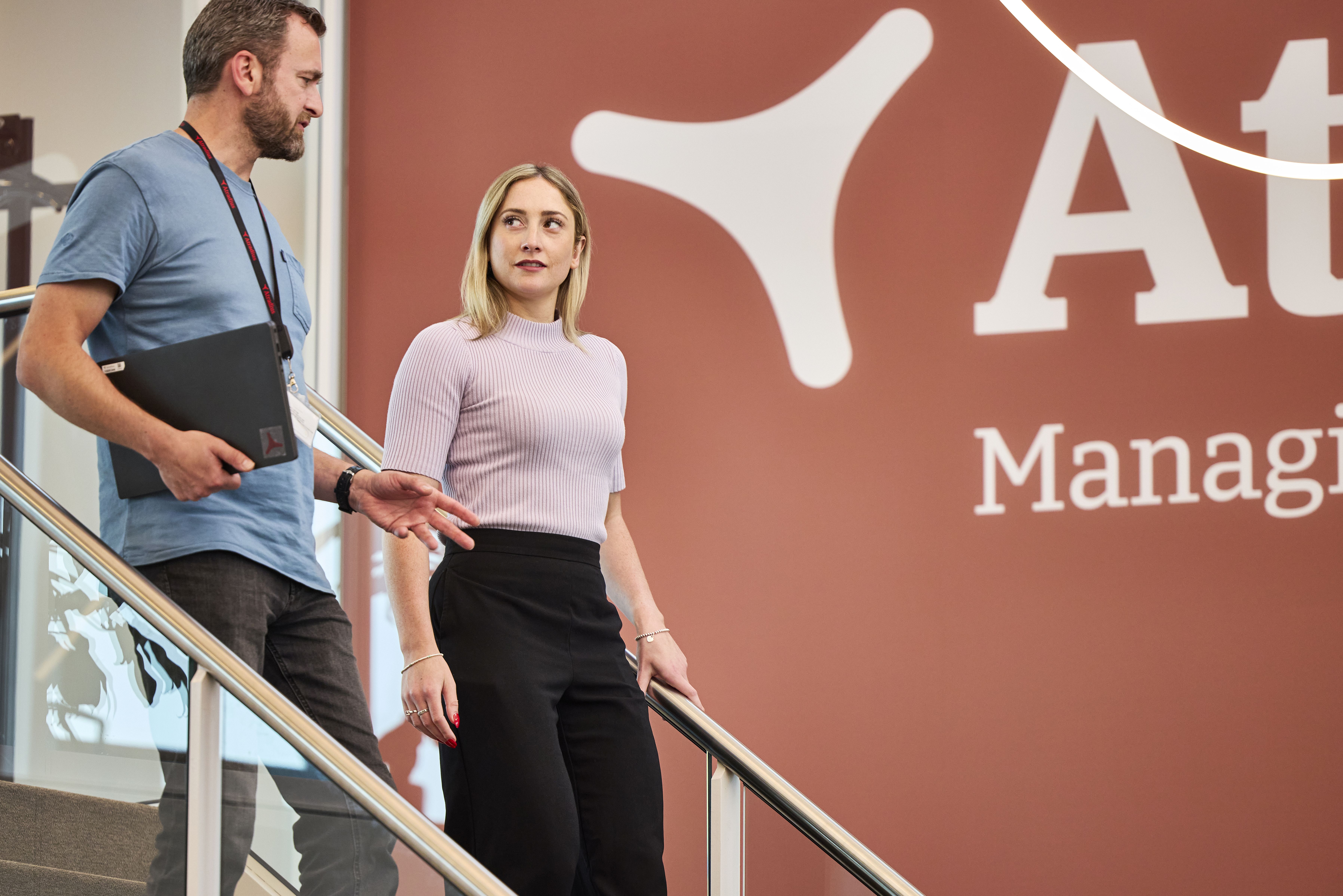 Two Atradius colleagues talking while walking downstairs