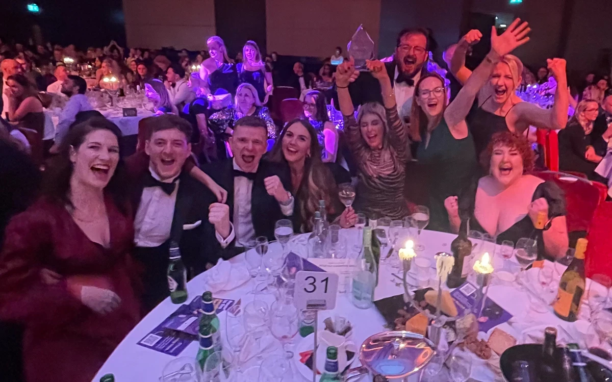 Four people stand together in an Opencast office reception area, posing in front of the company logo on a tiled counter.