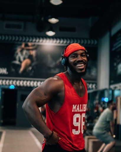 A smiling man in a red jersey standing confidently in a gym. Text: Zane Mitchell – Wellness Coach.