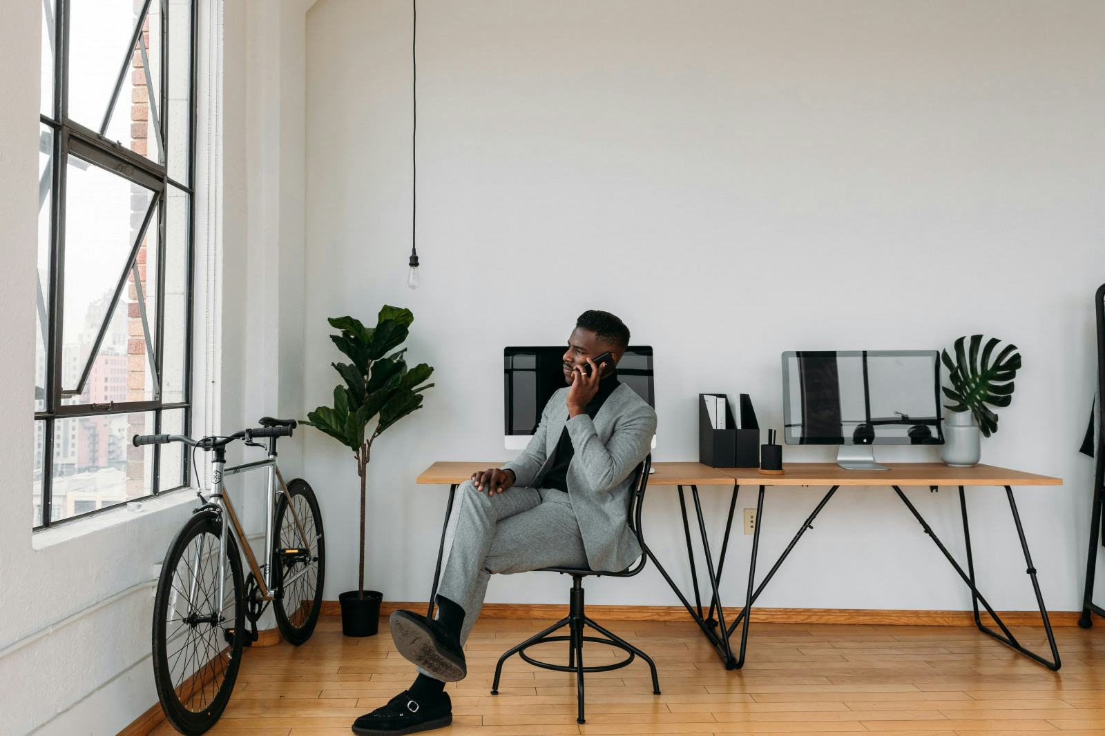 A well-dressed man in a suit sits on a chair in an office, surrounded by a professional environment and office decor