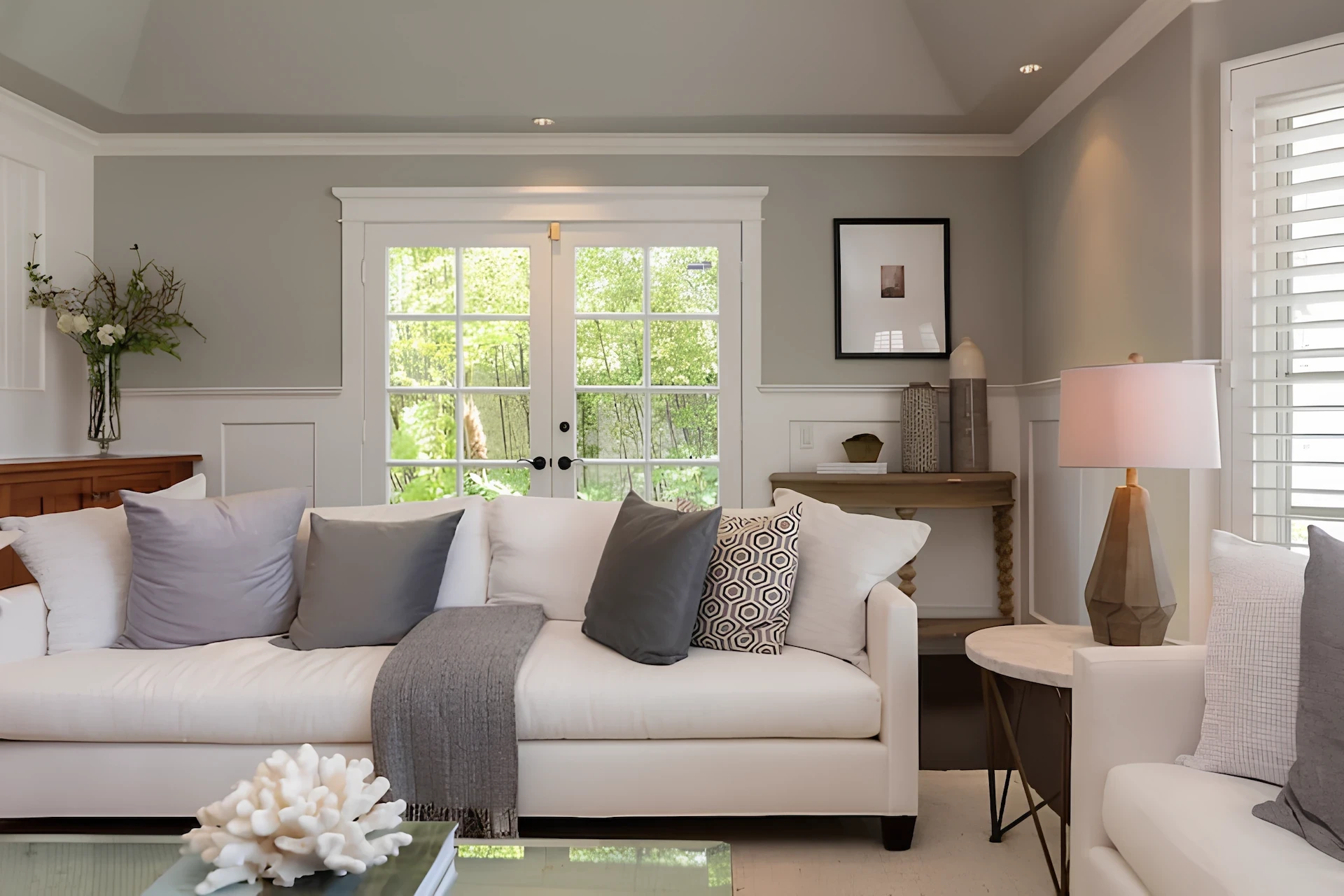 Port Streets Remodel' snug living corner with white couch, wooden console, art, and outdoor view.