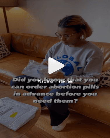 A person sitting on an orange couch opens a package with a white mailing bag on a wooden coffee table, wearing a gray sweatshirt with a blue globe logo, indoors, with text overlay discussing ordering abortion pills in advance.