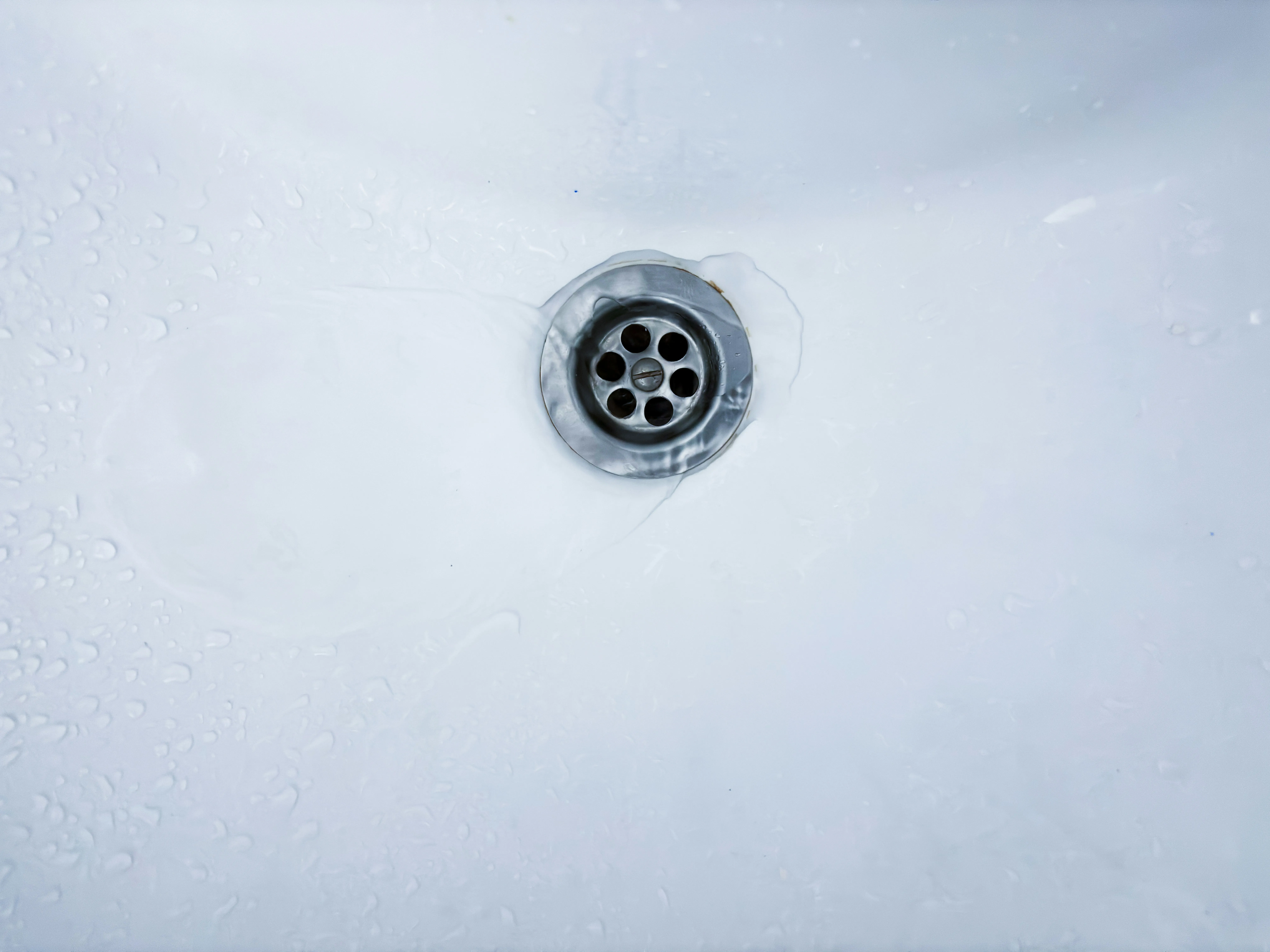 Water draining through the waste outlet of a white basin