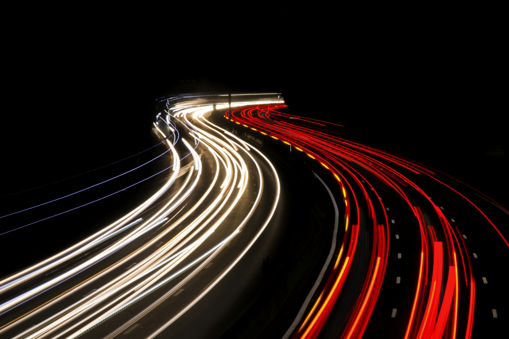 Fast Decisions — long-exposure light trails glowing orange on a black highway