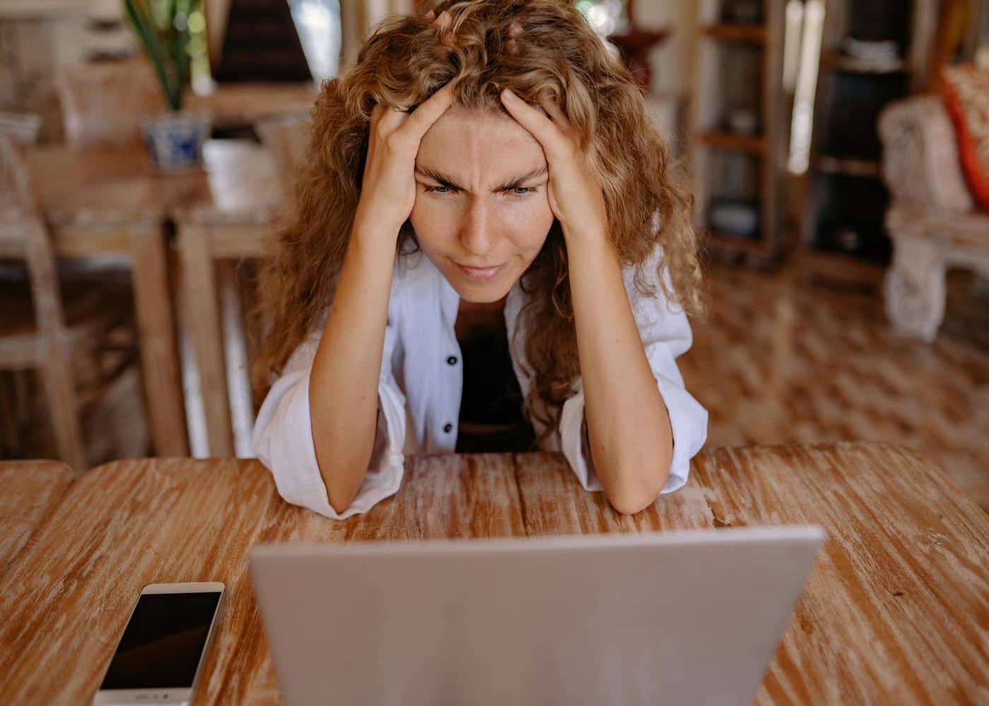Morning meditation for anxiety - Woman sitting in front of a laptop and holding her head