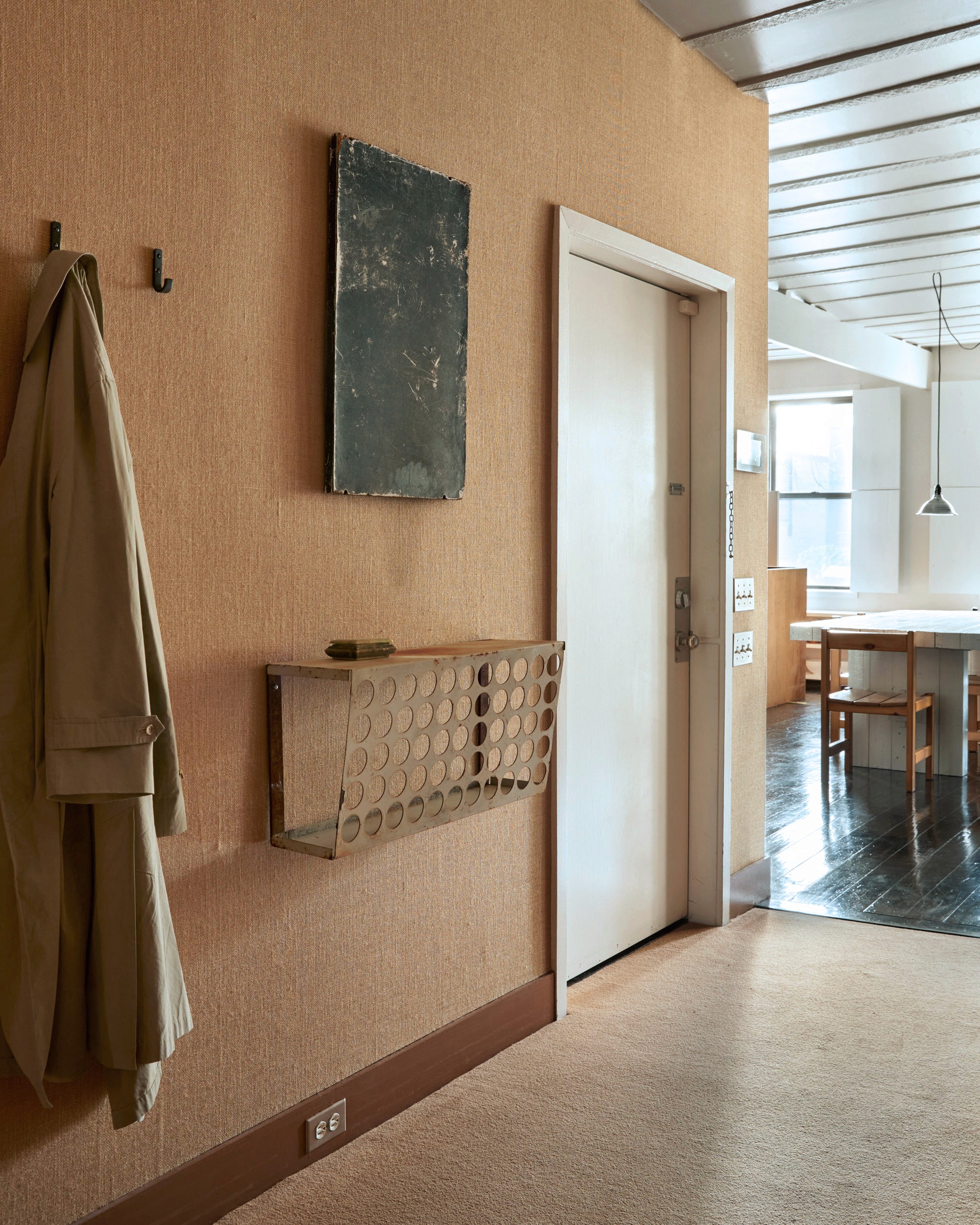 Apartment entryway with wall-mounted metal key drop and minimalist artwork.
