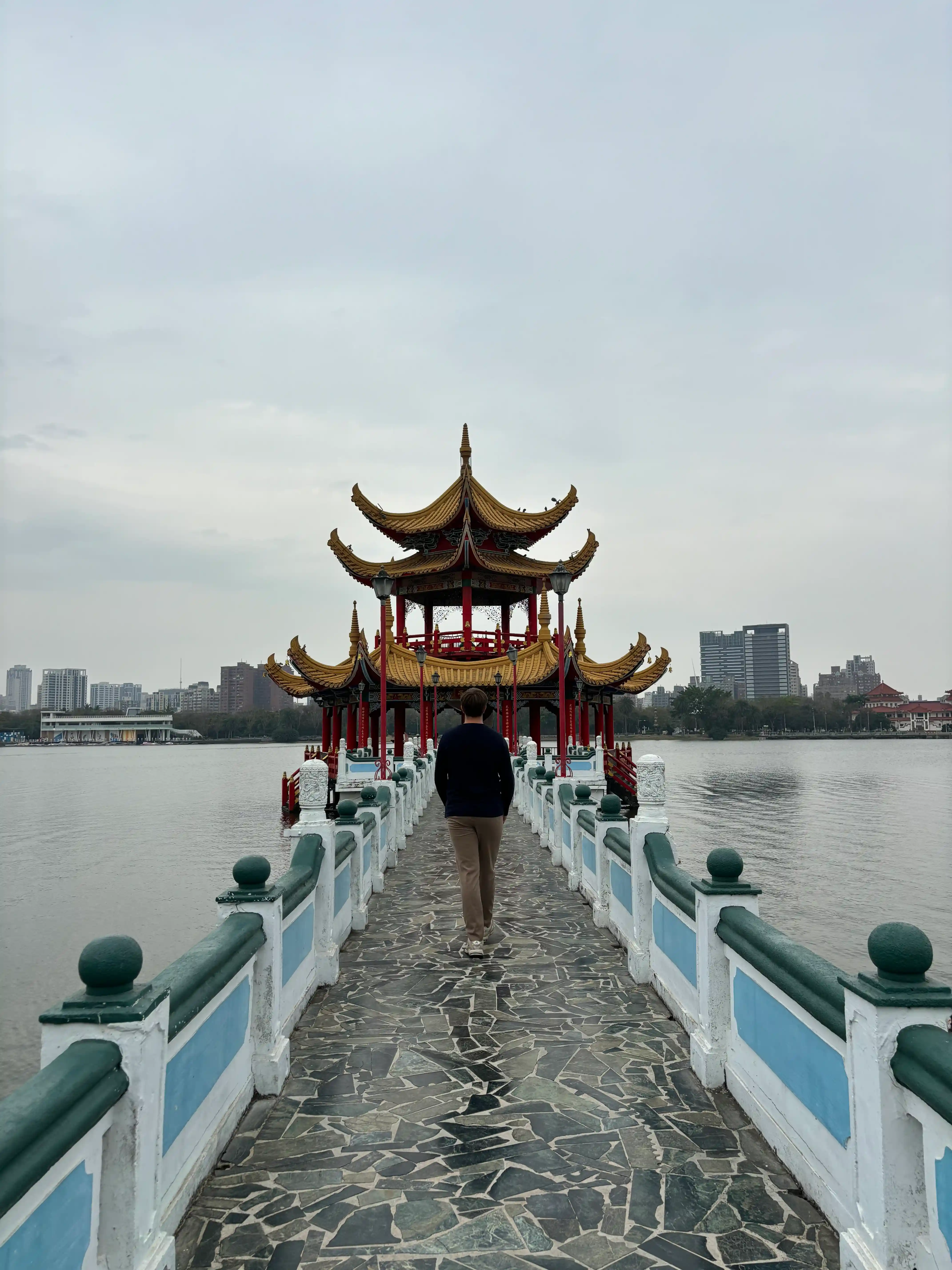 man op een stenen pad over het water naar een tempel midden op het meer