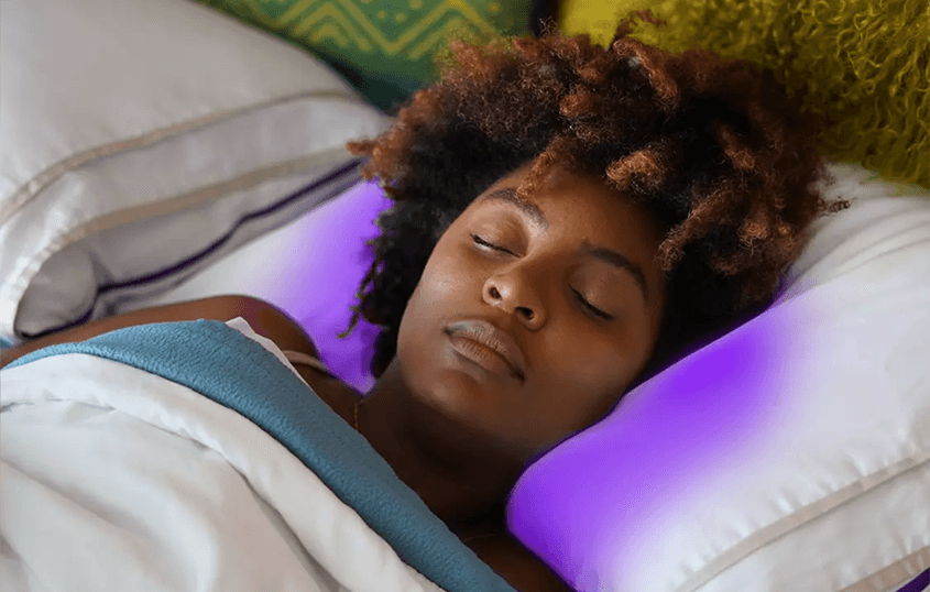 Woman sleeping comfortably on her back on a PureFlow pillow, with a purple glow highlighting the pillow area associated with reduced friction and improved sleep comfort.