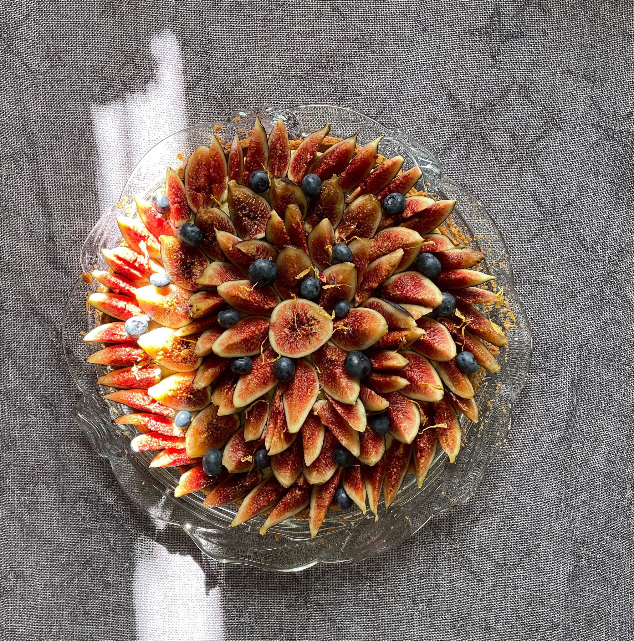 Overhead view of a fig-decorated cake on a glass plate.