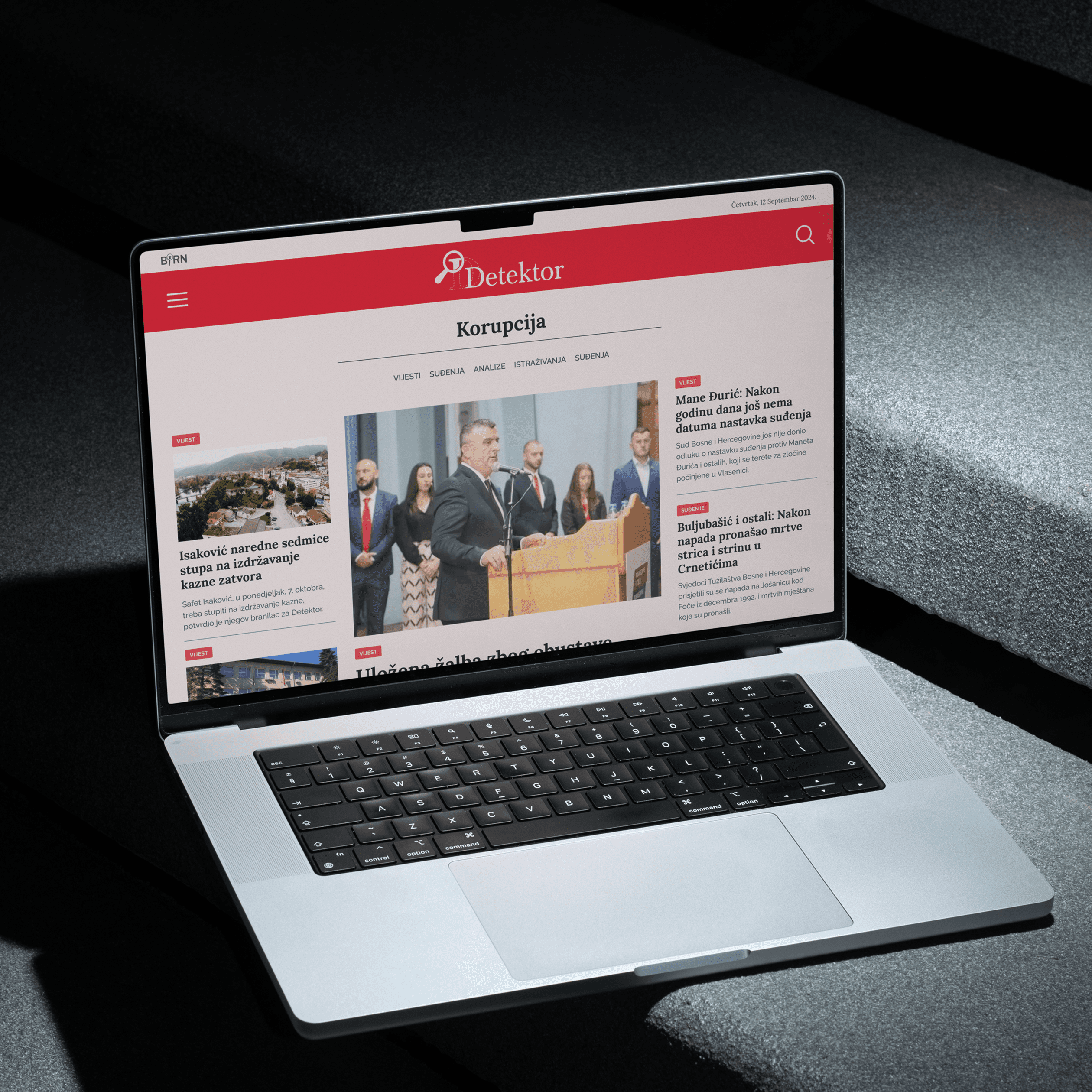 A laptop placed on concrete stairs, its display showing the news page of detektor.ba, designed by ofc. Studio.