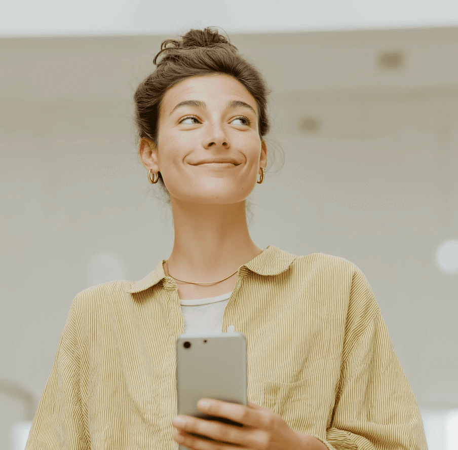 Woman in yellow striped shirt smiling while holding smartphone
