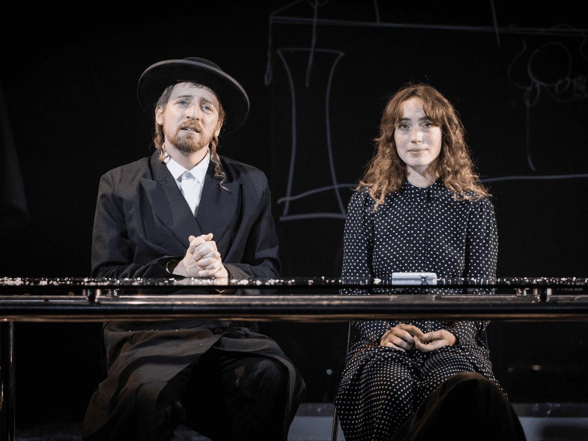 Two characters seated side by side at a table in a tender moment from The Wanderers.