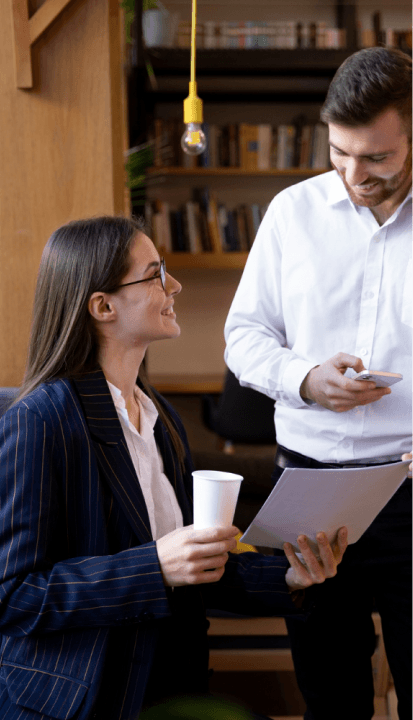 A man and woman in business attire are engaged in discussion while examining a tablet together.