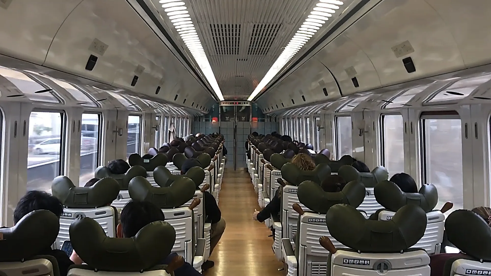 The interior of a Kyushu limited express with green seats, en route to Kurokawa Onsen