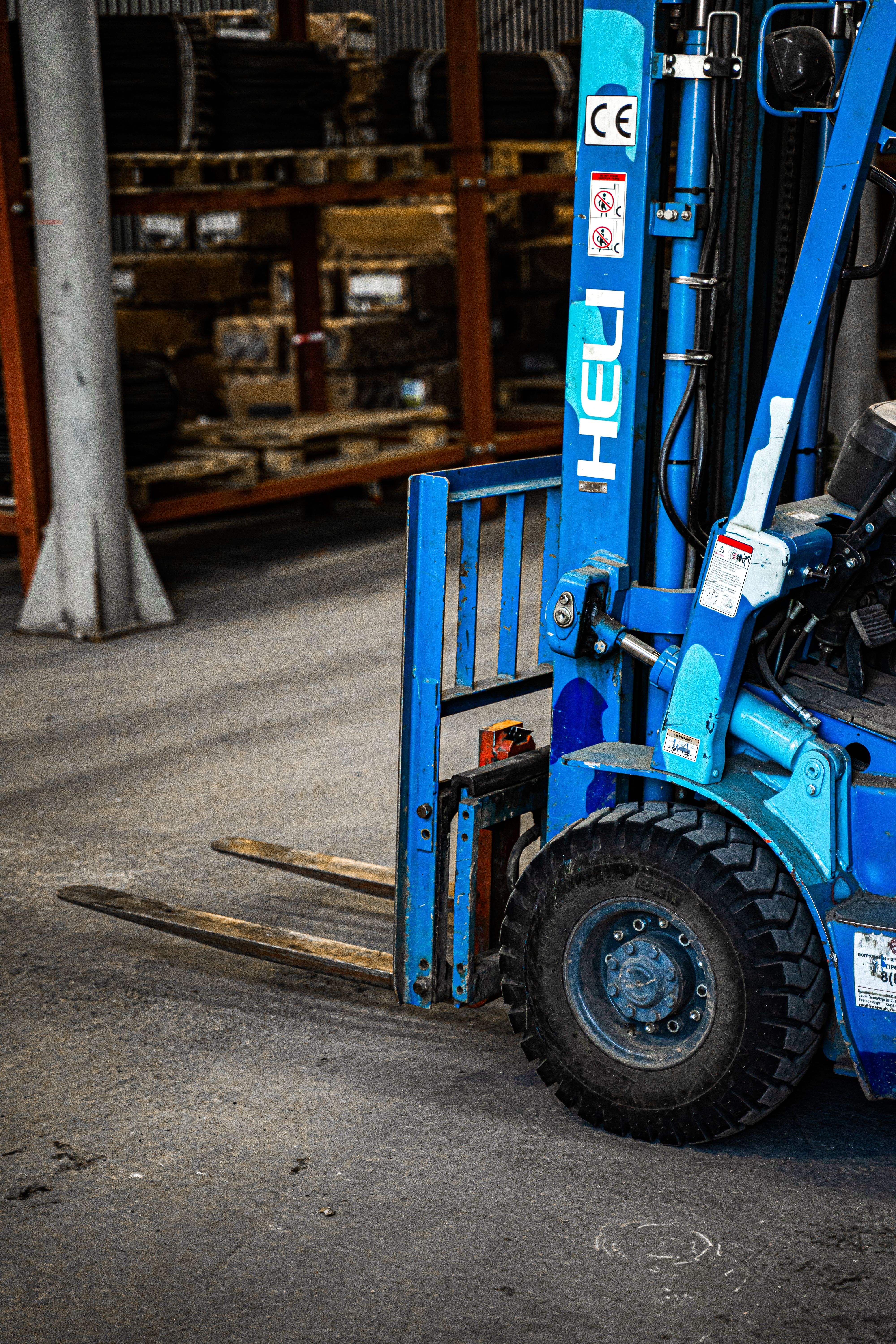 blue-forklift-inside-an-industrial-warehouse,-parked-near-shelves-with-various-i - alex-urezkov (pexels)