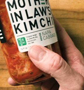 a jar of kimchi in a hand