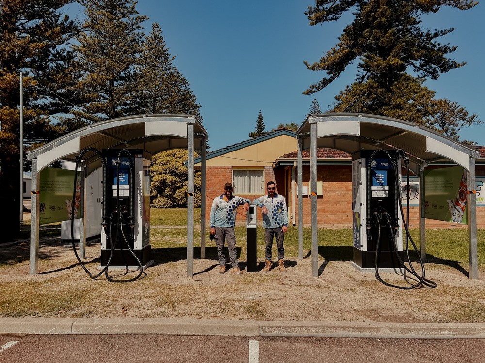 Powerhouse Renewables Group team members pose next to electric vehicle fast chargers in Western Australia.