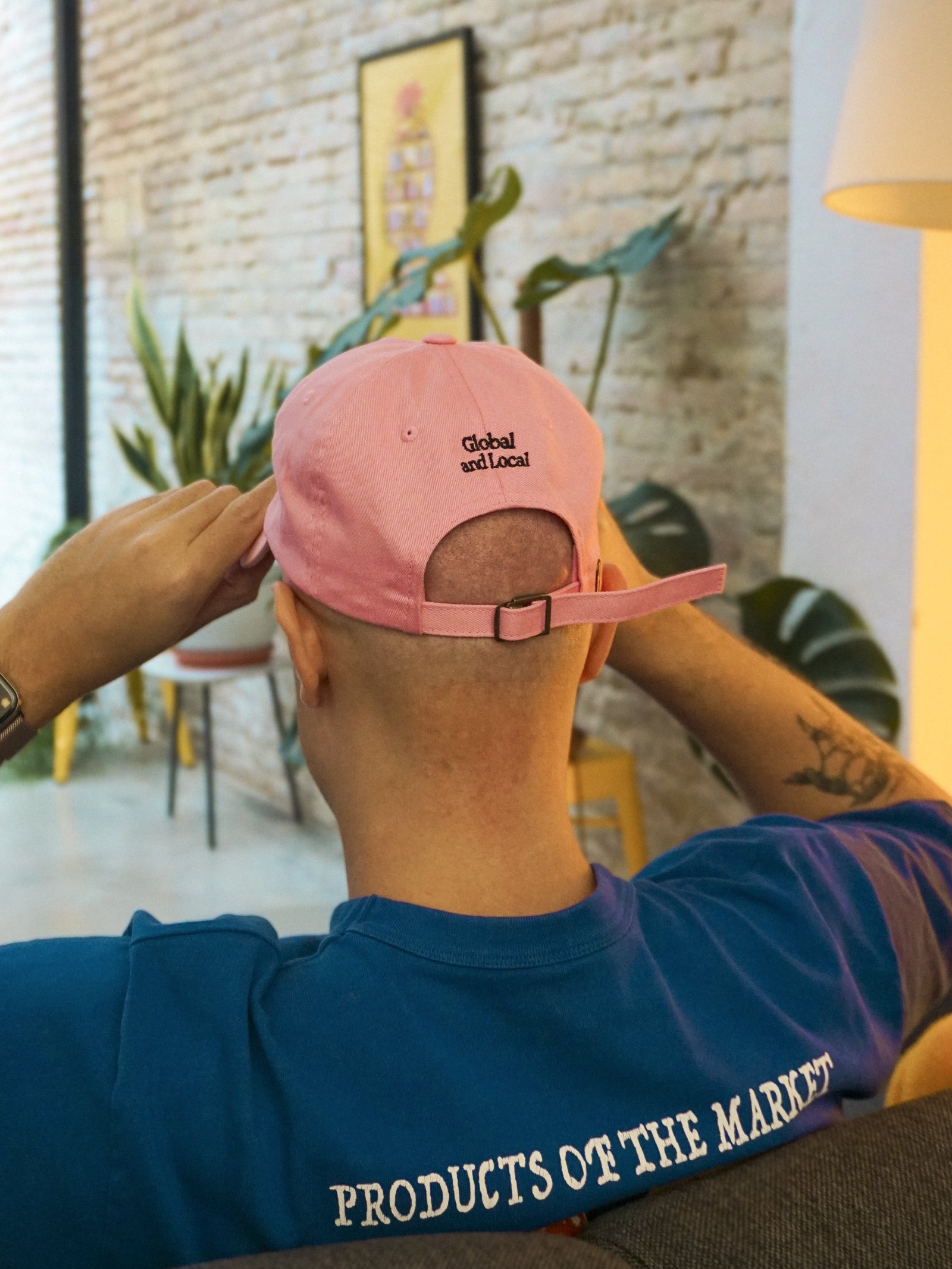 Person wearing a pink cap and blue shirt with text in an indoor setting