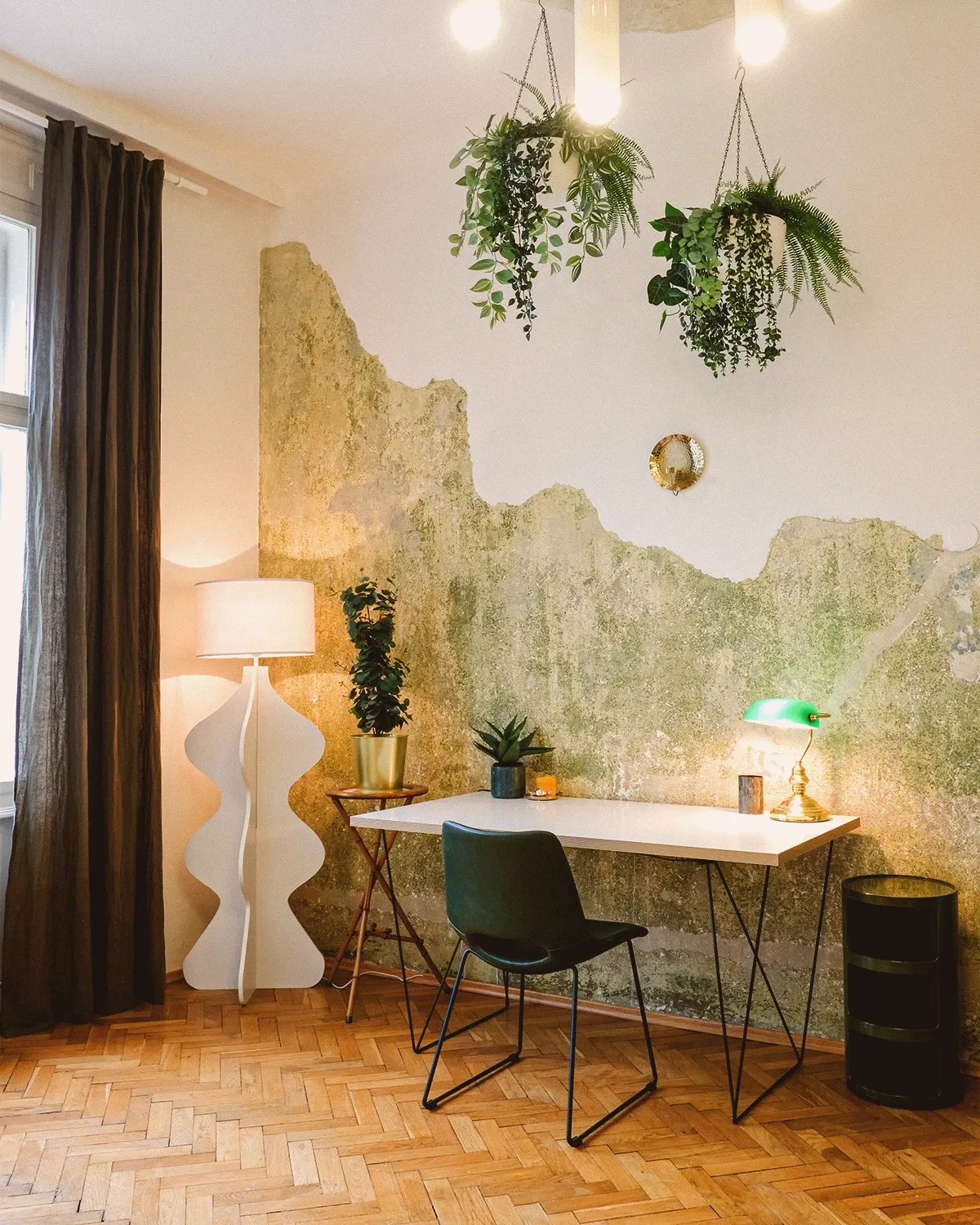 Boutique N°1 • workspace with a white desk, a green banker's lamp and hanging plants against a weathered wall