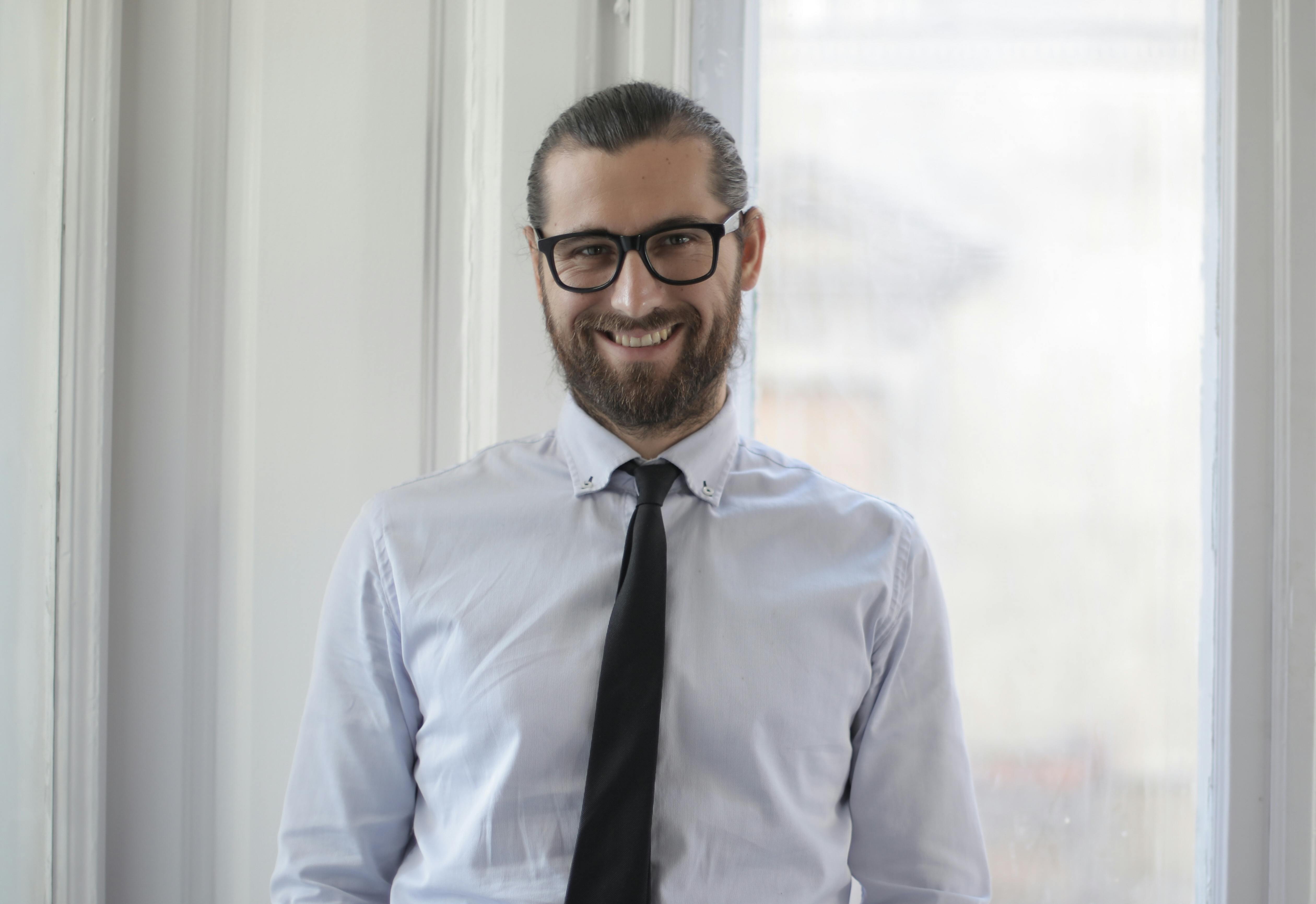 Man in glasses and tie smiling.