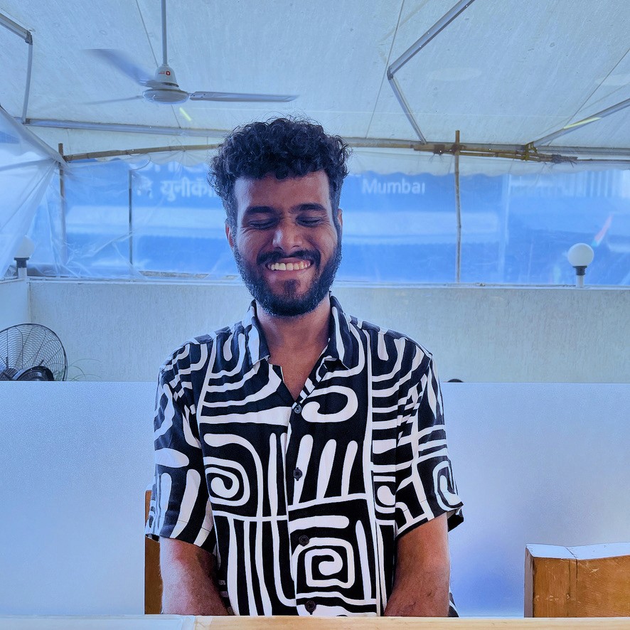 Anthony Stephen Mendes smiling in a black and white shirt with artistic design.