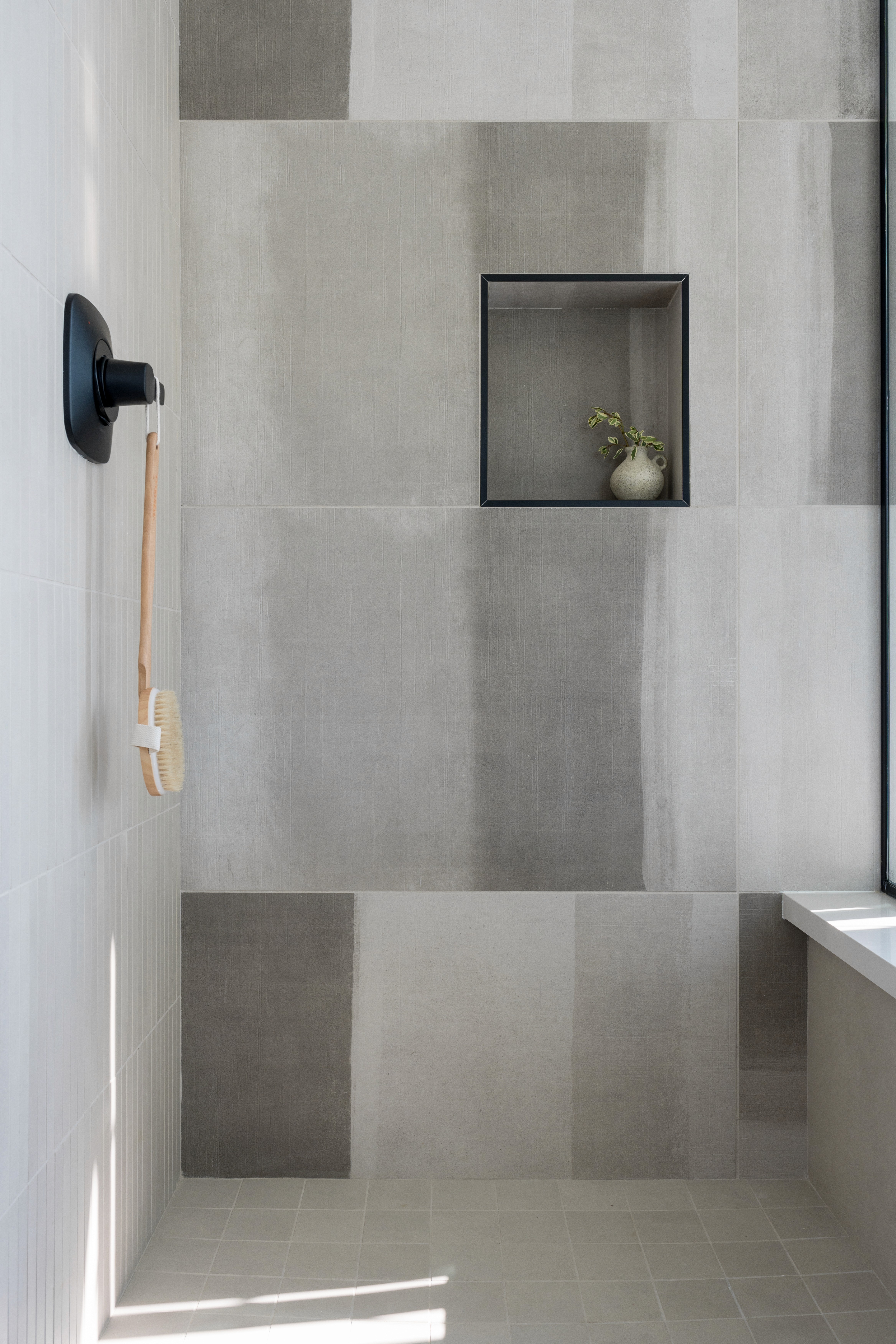 Primary shower with large grey and white tile wall and black hardware finishes by Jubilee Interiors in Arcadia, California