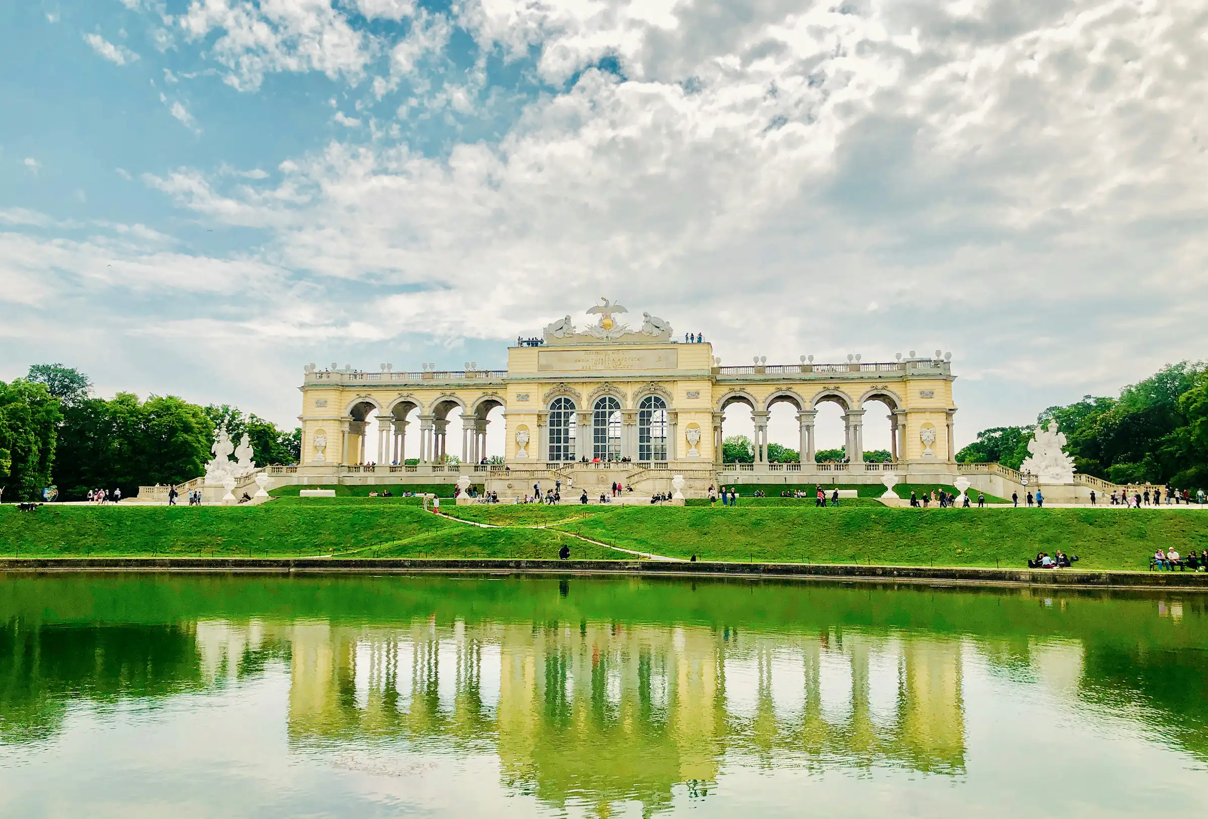 Wien-Hietzing, Gloriette im Schlosspark Schönbrunn mit Spiegelung im Teich unter Wolkenhimmel