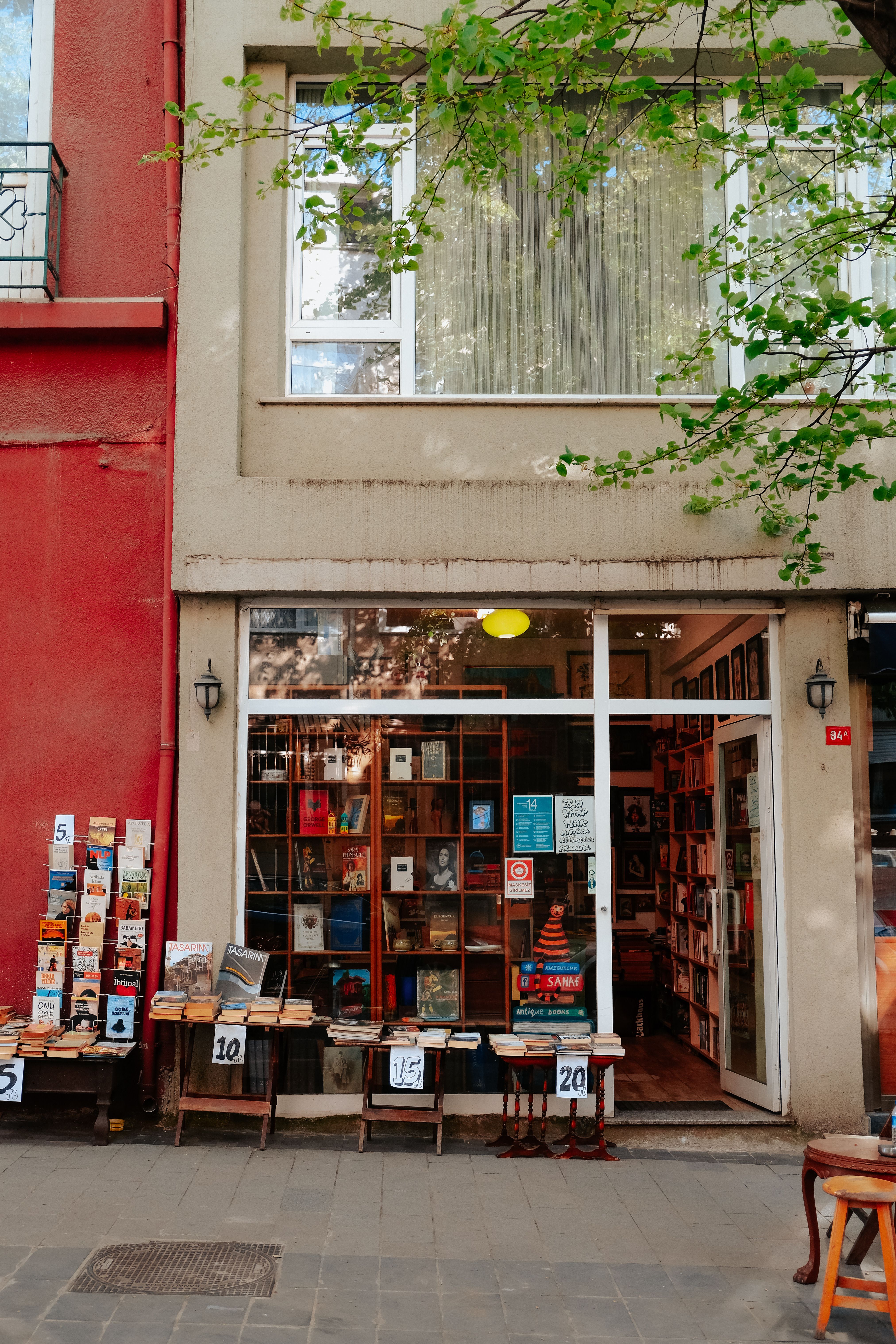 Books fill shelves and tables outside a small bookshop, creating an inviting street-side display.