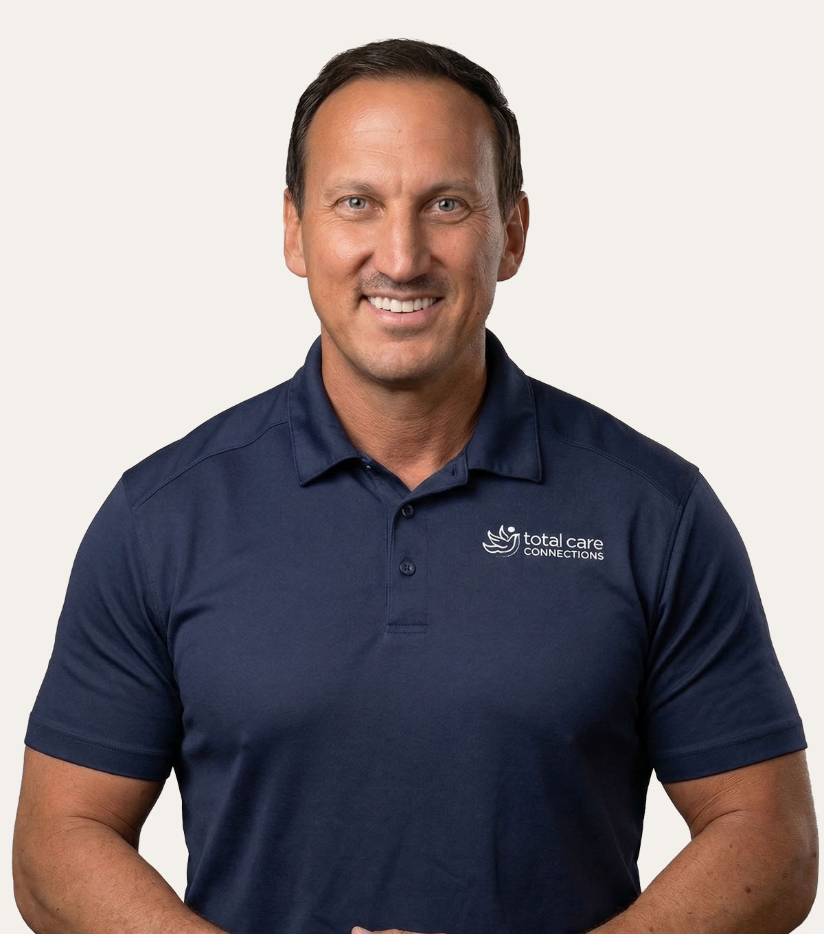 Man wearing a navy blue polo shirt with a white logo for Total Care Connections.