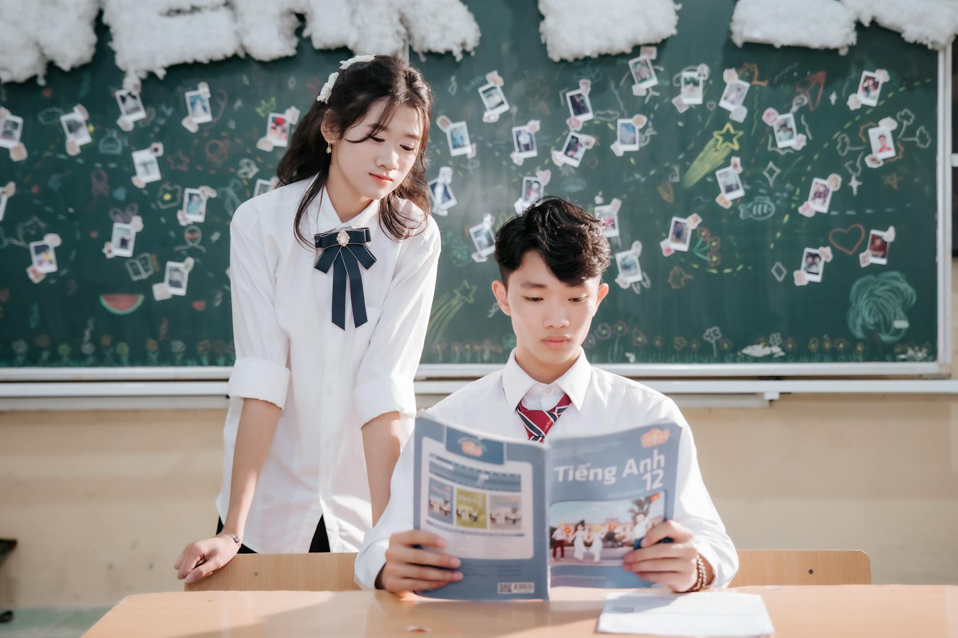 A teacher reading from a detailed instructional manual while students follow along in matching workbooks.
