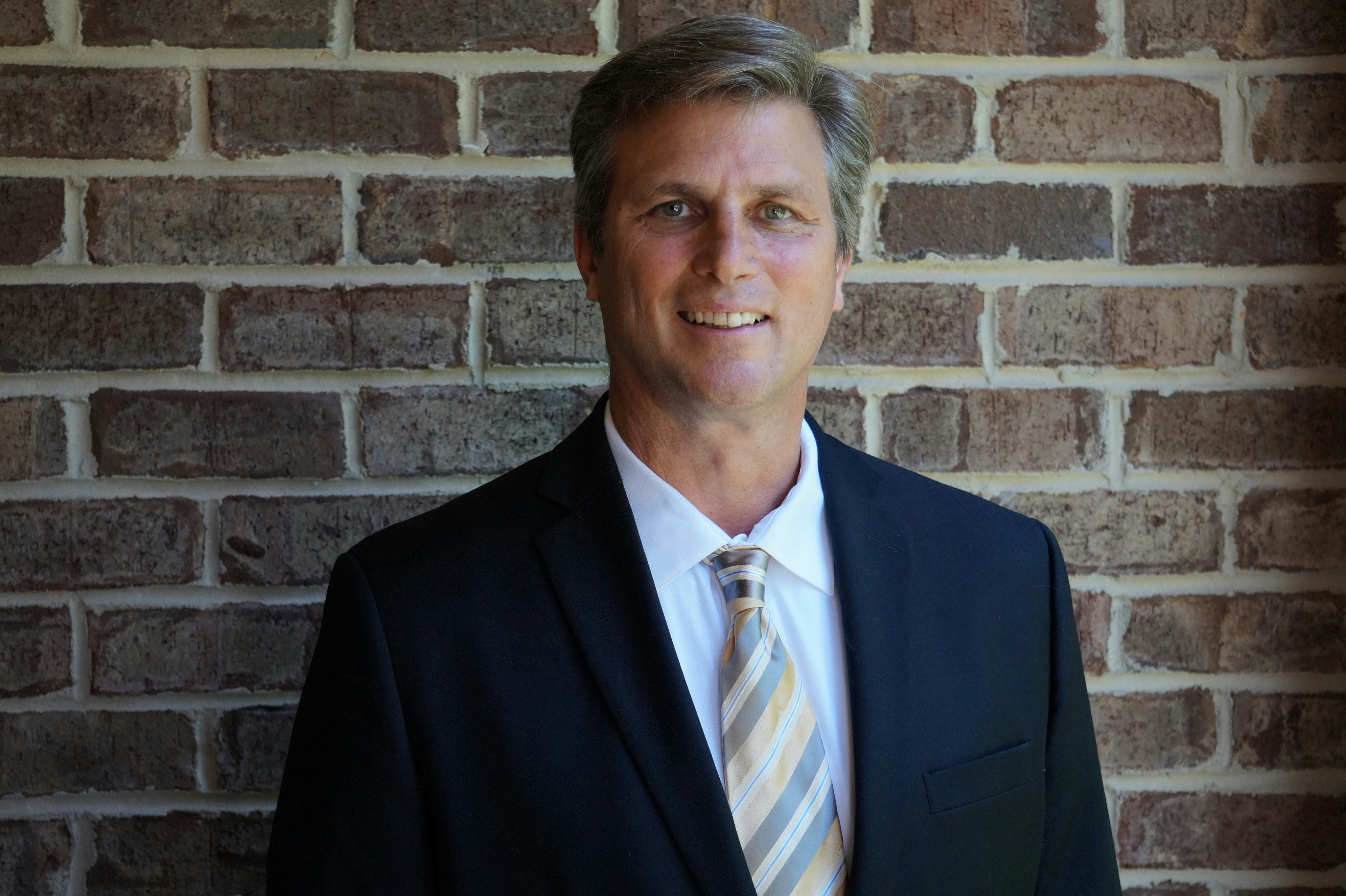 An executive posing for his professional headshots in an outdoor setting for his LinkedIn