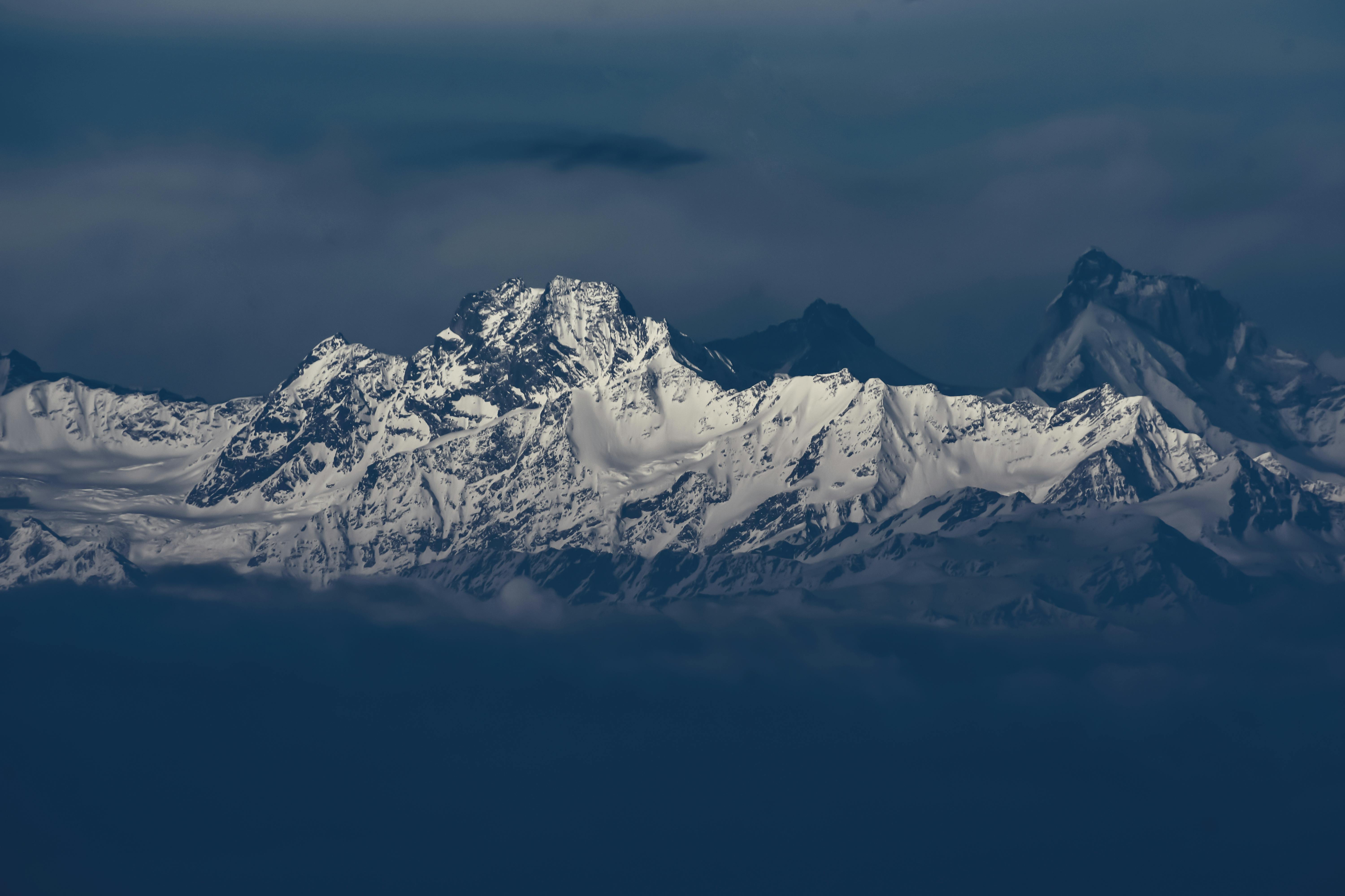 Snow covered mountain range under dark clouds