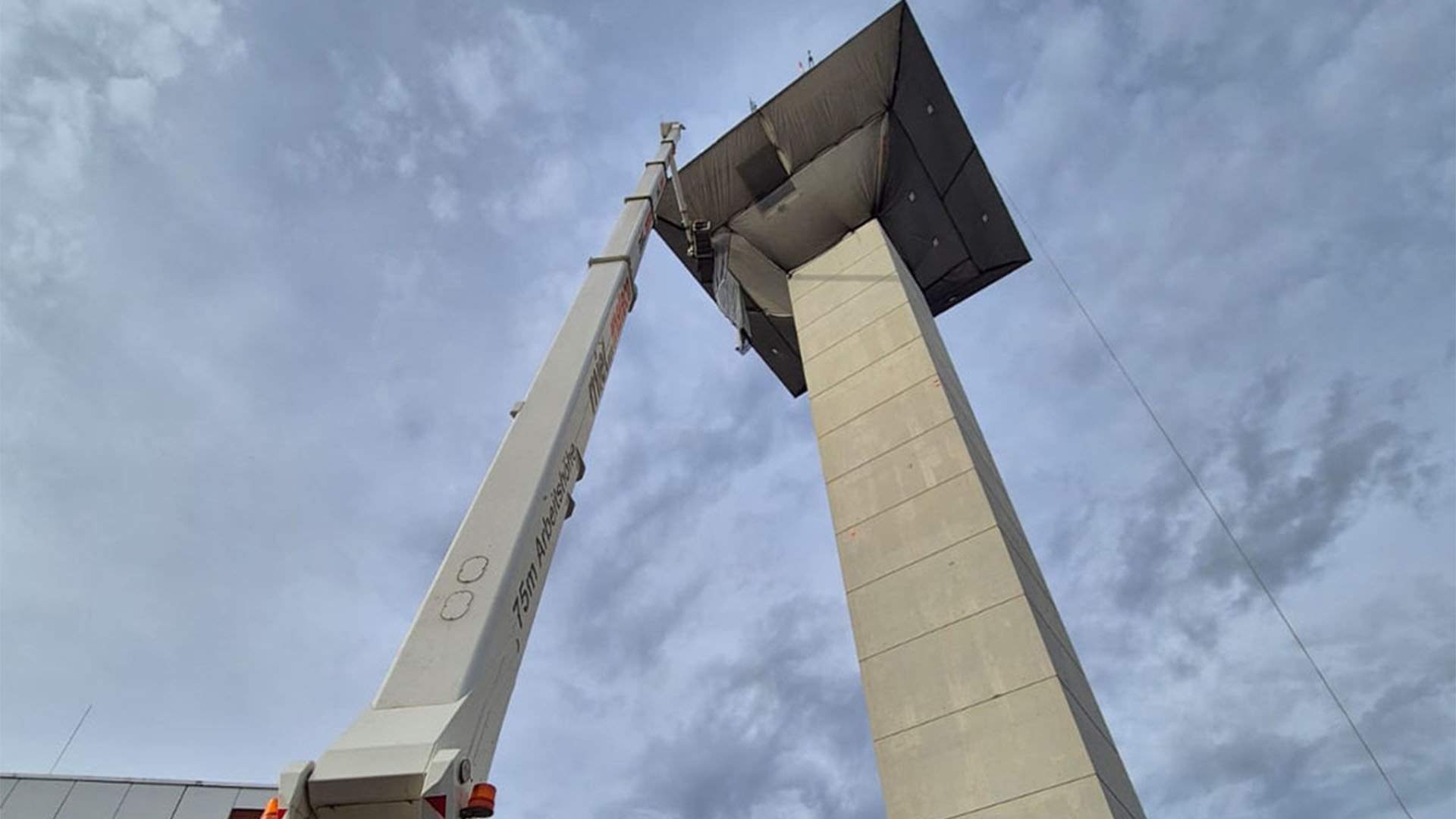 Young woman smiling brightly near a frosted glass whiteboard, bathed in warm, natural light in a modern office setting.