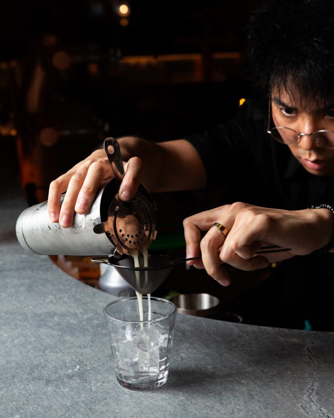 Close-up of a dark green leaf showing its textured surface and central vein against a muted background.