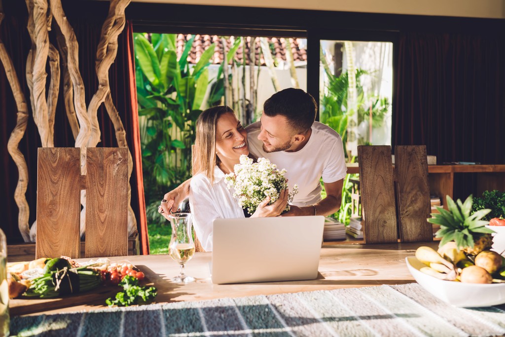 Happy couple planning wedding together on laptop