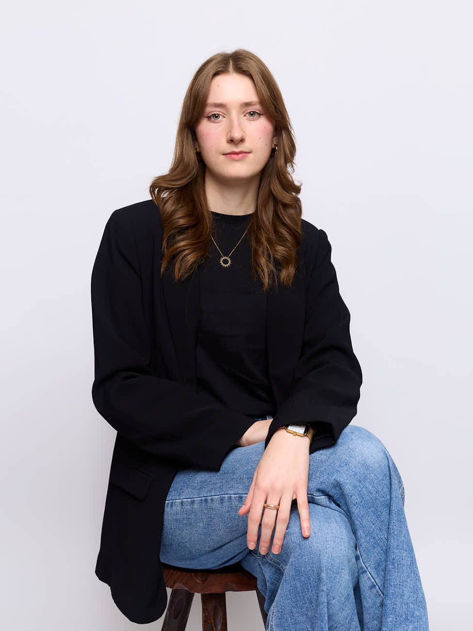 Portrait corporate professionnel en studio d'une architecte d'intérieur basée à Lille, assise sur fond blanc, style décontracté chic.