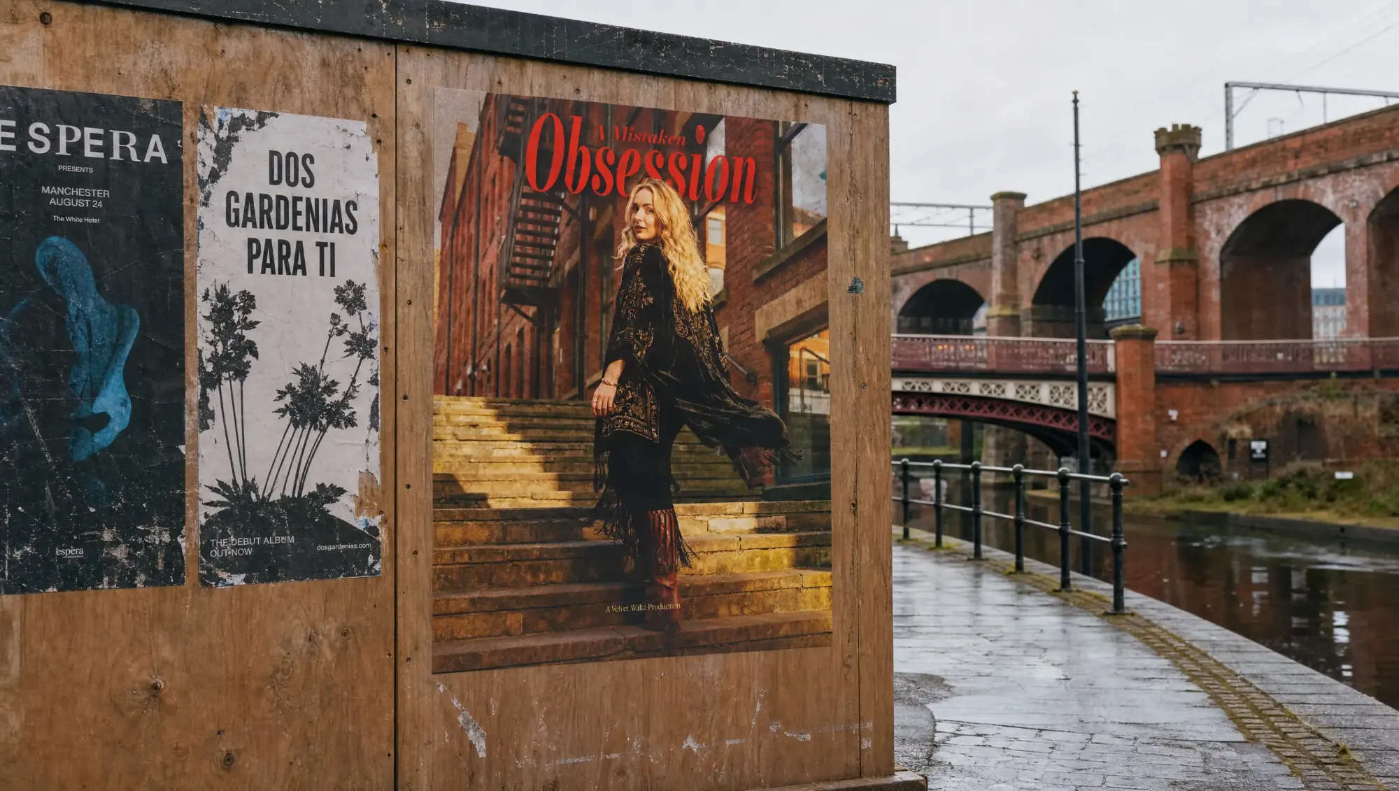 A Mistaken Obsession poster pasted on a hoarding beside a canal and railway arches