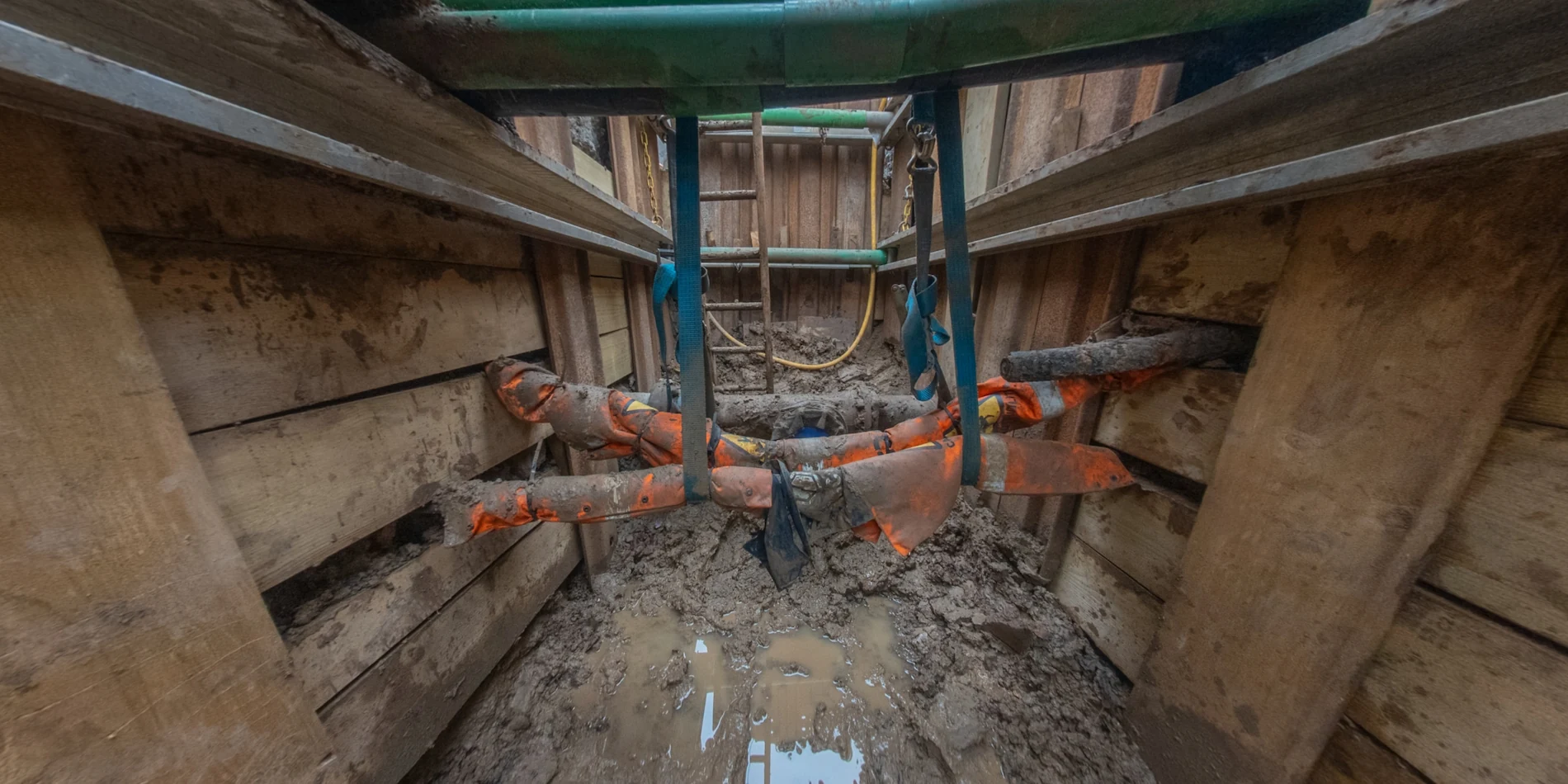 Close-up inspection of exposed underground pipes wrapped in safety marking, essential data for a utilities survey.