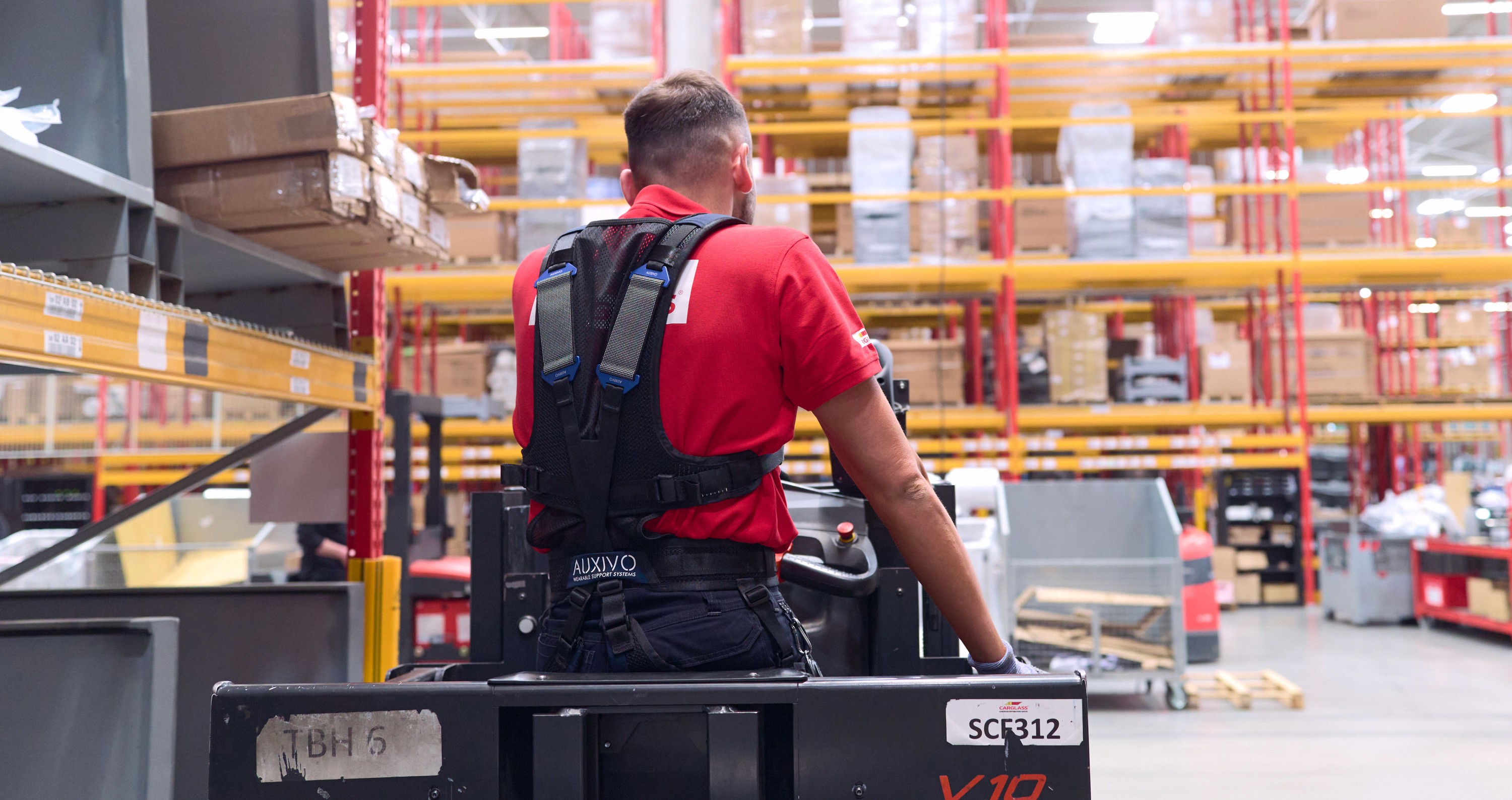 Travailleur d’entrepôt portant un exosquelette dorsal LiftSuit d’Auxivo pour réduire la fatigue lors de la manutention et de la préparation de commandes