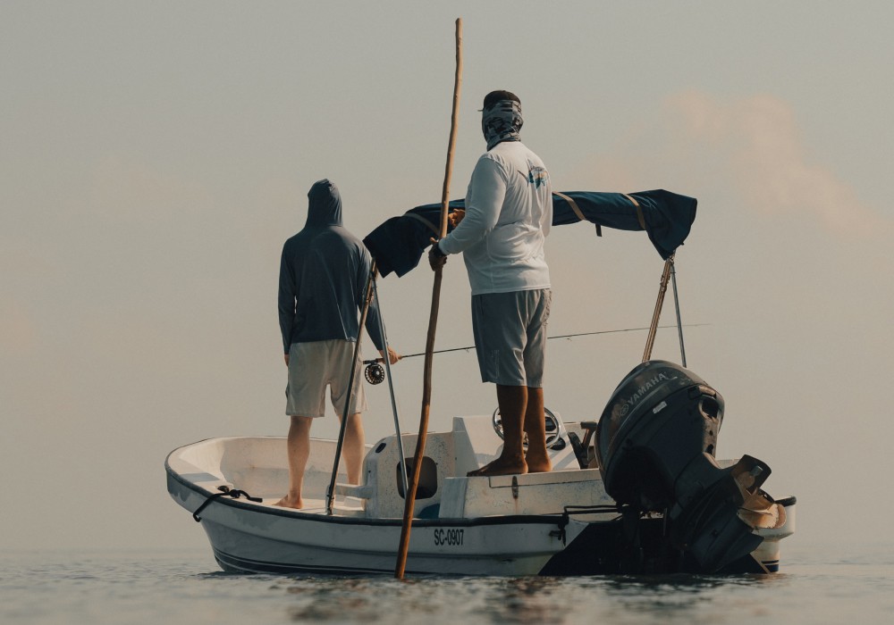 Fly fishing guide Marlon Leslie poling his boat on a shallow flat with an angler in the front of the boat