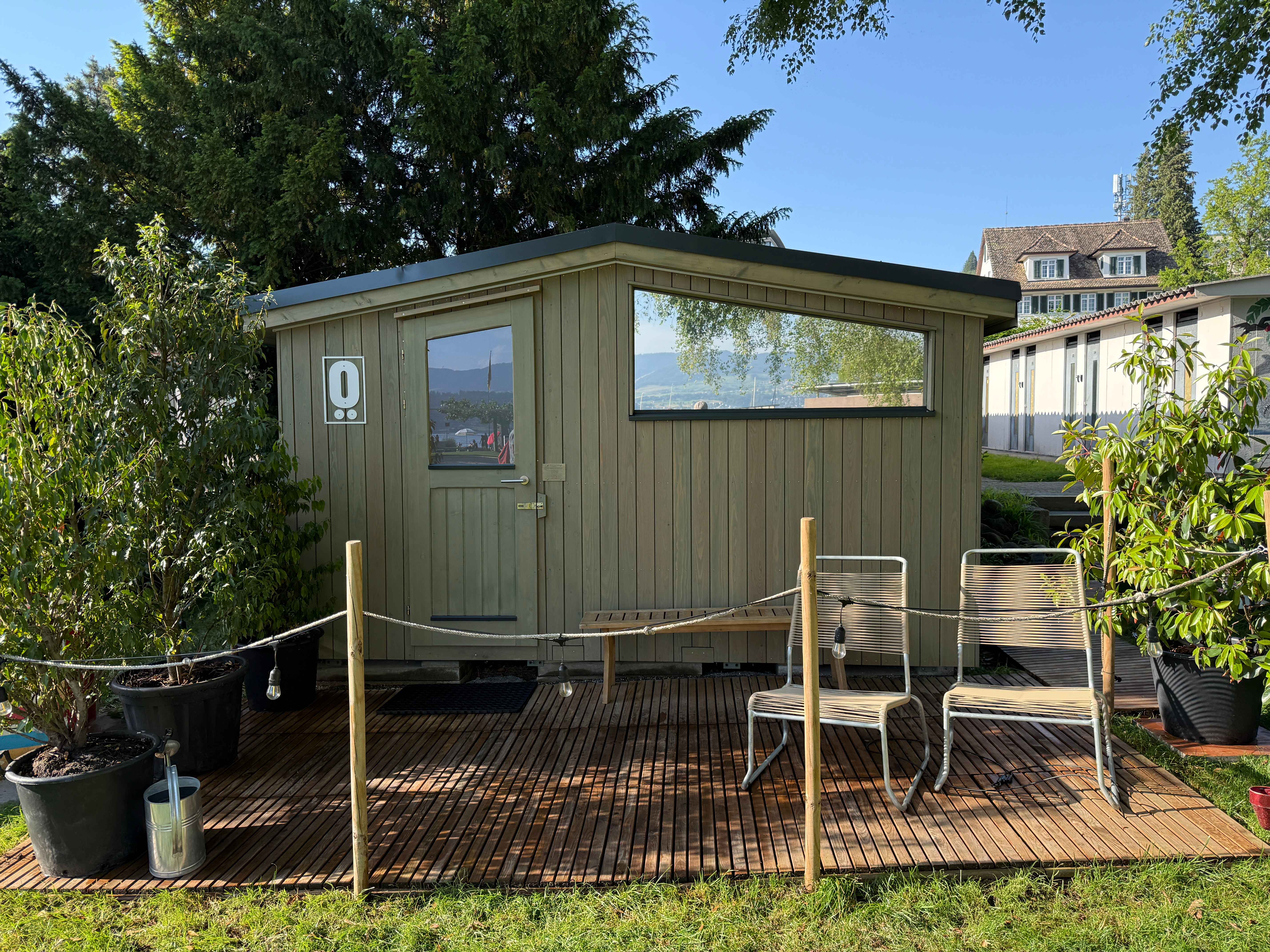 Mobile LÖYLY-Sauna im Strandbad Männedorf, eingebettet zwischen Bäumen und Natur für Sauna- und Wellness-Erlebnisse am Zürichsee.