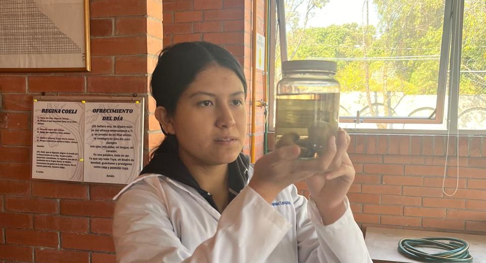 Miriam conducting a science experiment and holding up a glass jar containing a dissection